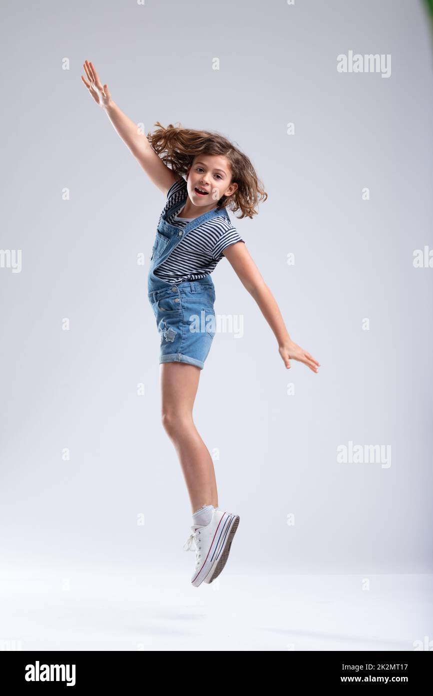 Giovane ragazza che salta in aria con le braccia allungate Foto Stock