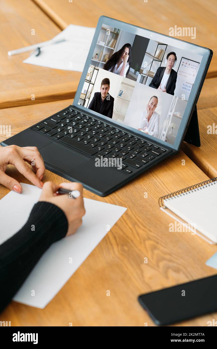 Intervista video. Riunione remota. Teleconferenza internazionale. Donna d'affari stanca colleghi diversi guardando noiosa presentazione sullo schermo del notebook i Foto Stock