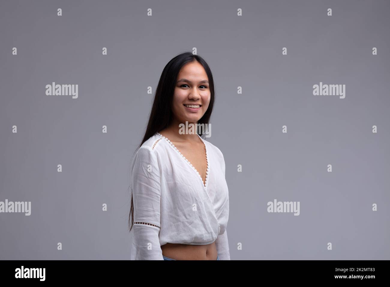 Attraente donna toung con un sorriso amichevole e lunghi capelli scuri Foto Stock