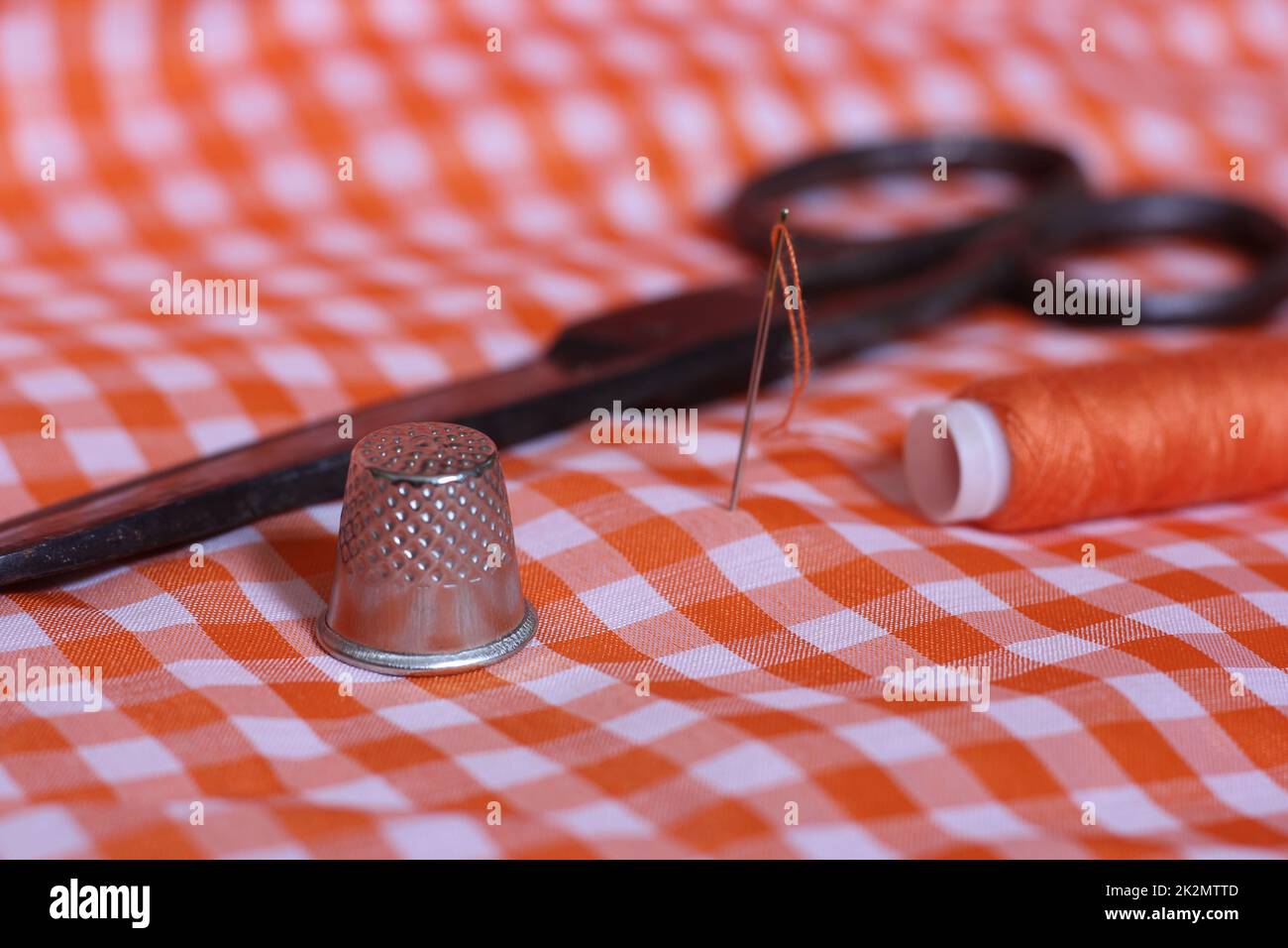 Tessuto a scacchi arancione e bianco con tamburo e rocchetto di filo arancione Foto Stock