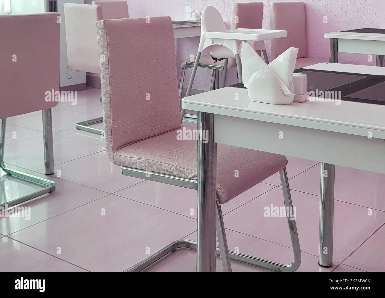 Interni eleganti e moderni con tavoli e sedie di design, tonalità rosa Foto Stock