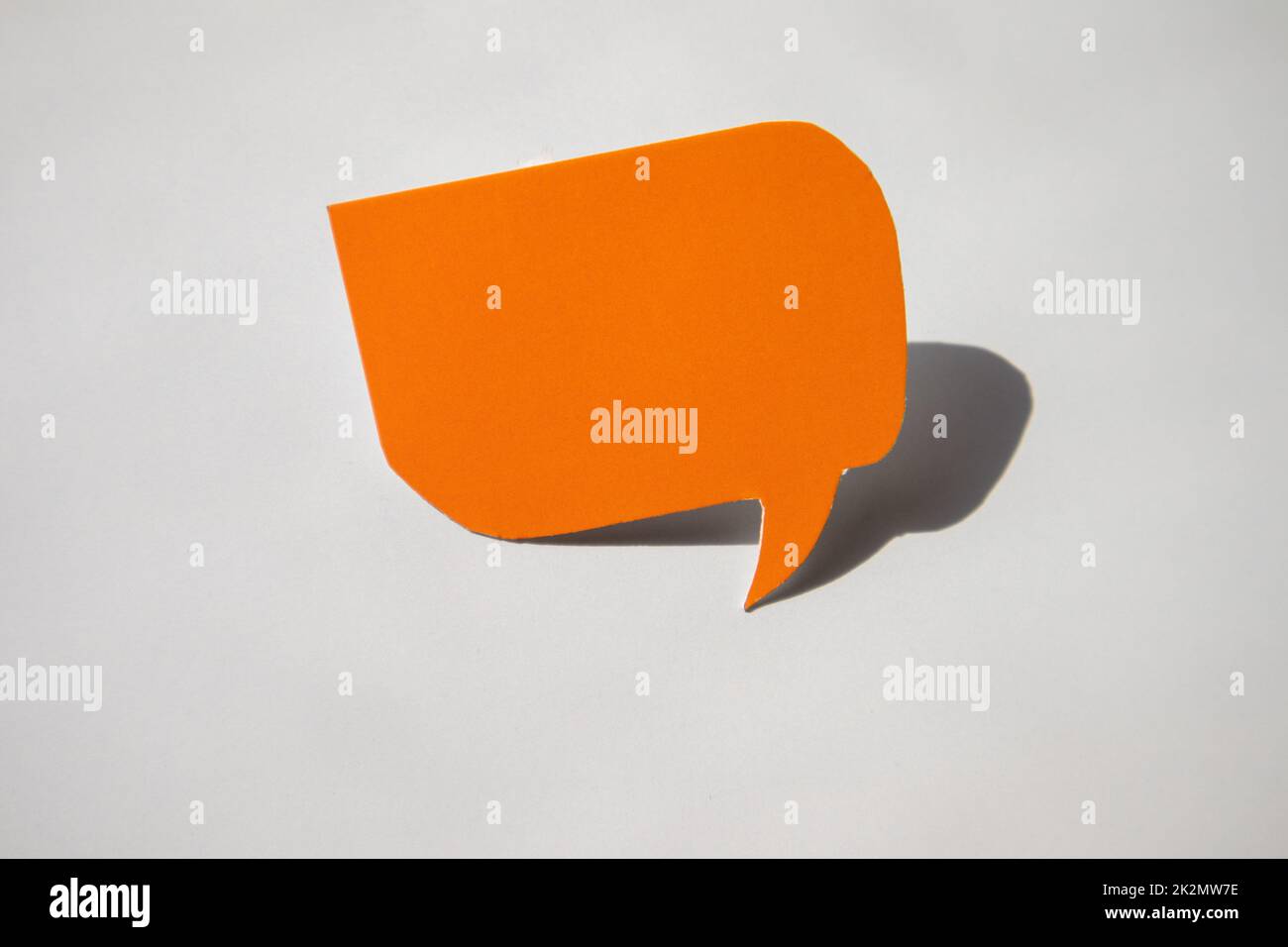 Un dialogo vuoto fatto di carta arancione con un fumetto di discorso su un pallone per il vostro disegno, un concetto di business su uno sfondo bianco con un'ombra dura Foto Stock
