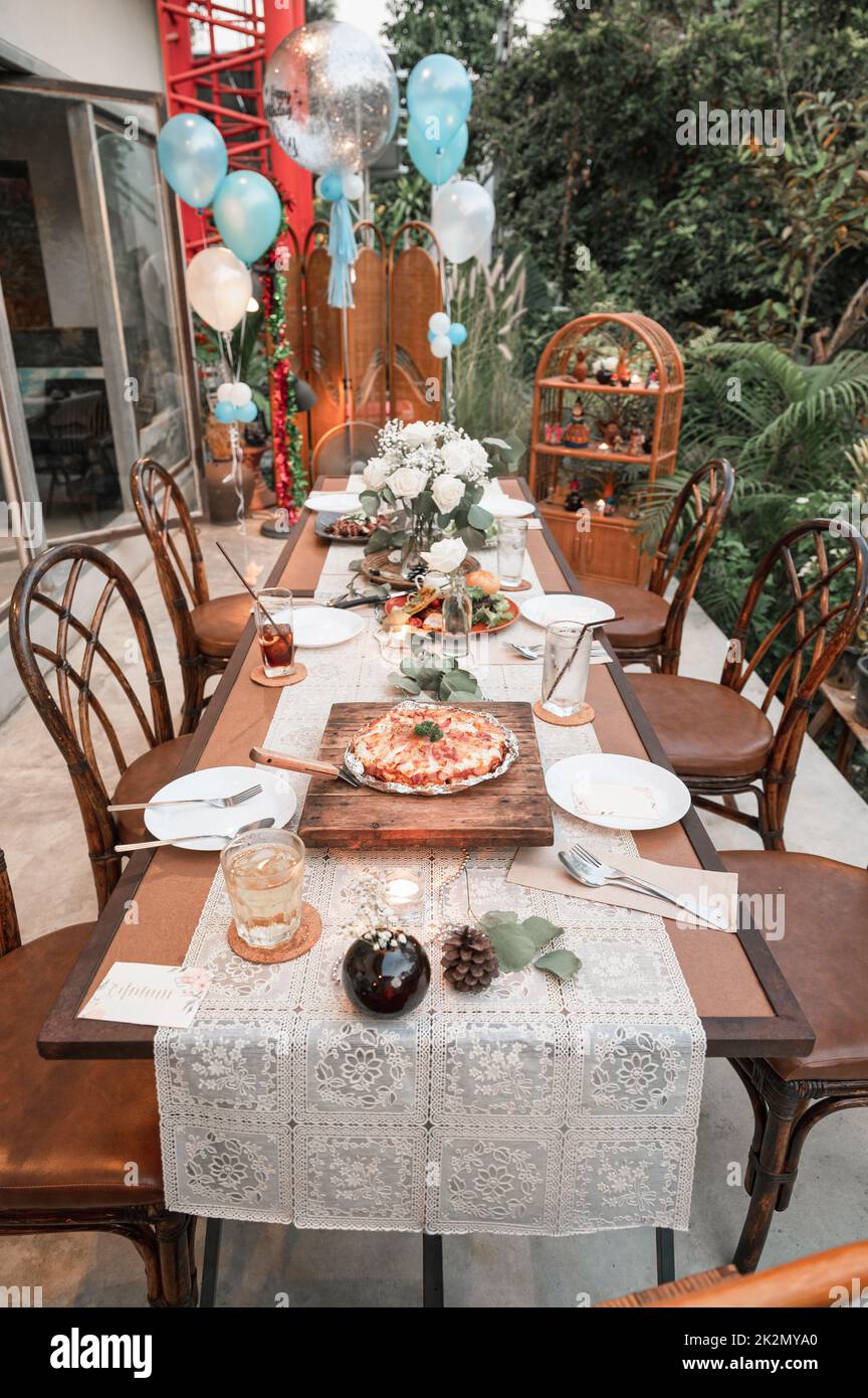 Antico tavolo da pranzo con pizza, insalata, stoviglie, palloncino di  compleanno e decorazione oggetto su tavolo in legno nel giorno della  celebrazione Foto stock - Alamy