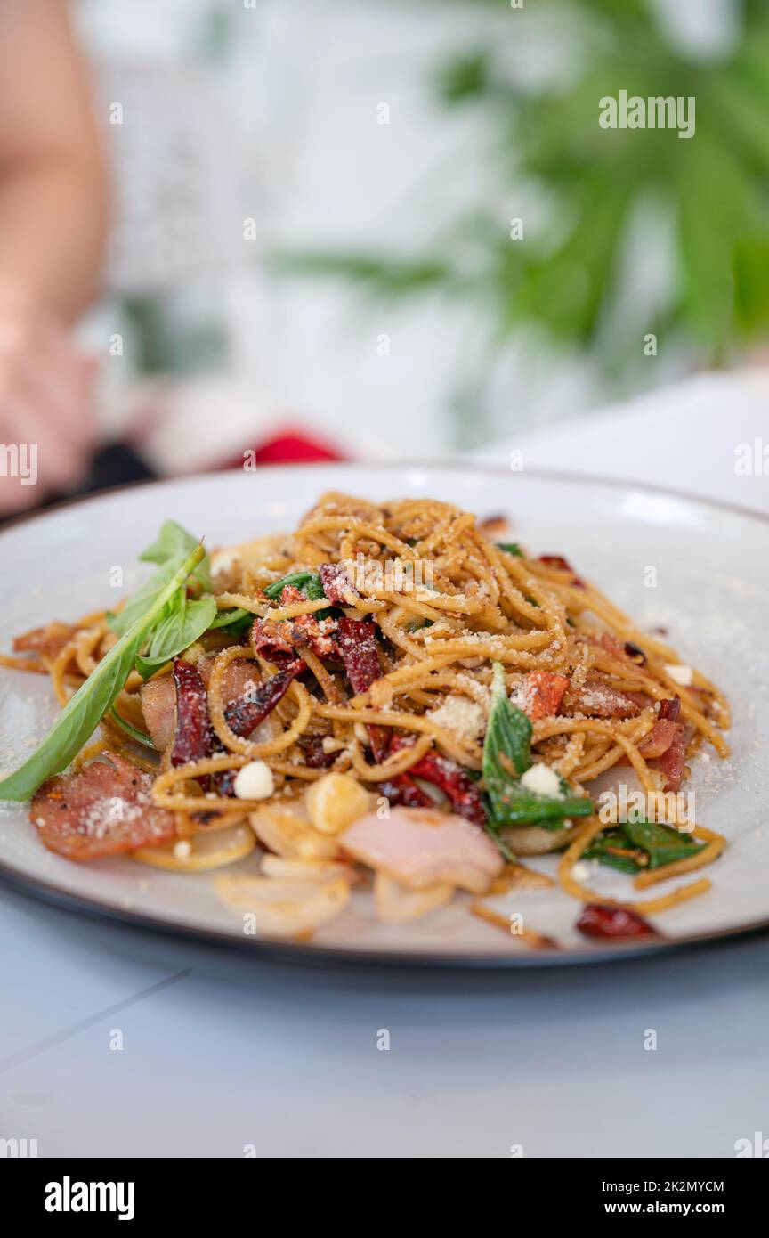 Spaghetti al peperoncino, pancetta, aglio, basilico e guarnire il formaggio in piatto bianco Foto Stock