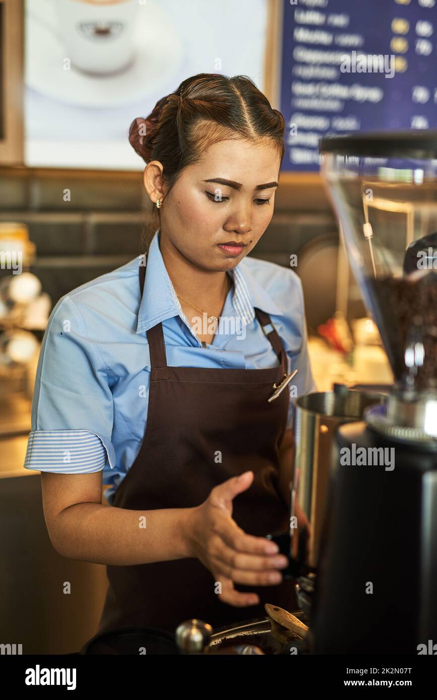 Pronto a servire il tuo calcio caffeina. Shot di un giovane barista che lavora dietro il registratore di cassa in un bar. Foto Stock