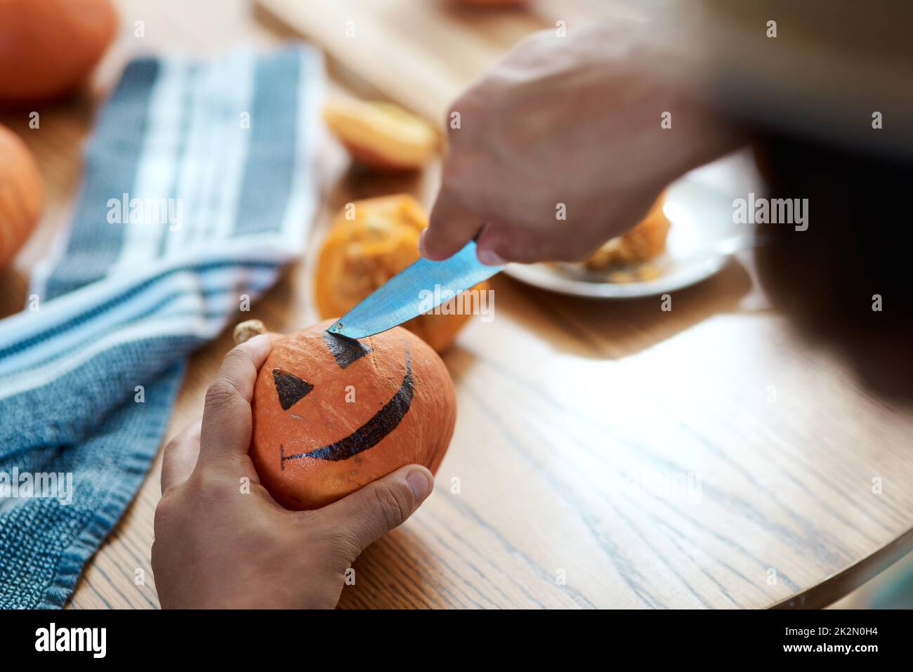Fai un tocco nello spirito di Halloween. Scatto di una persona irriconoscibile che intagliano una zucca a casa. Foto Stock