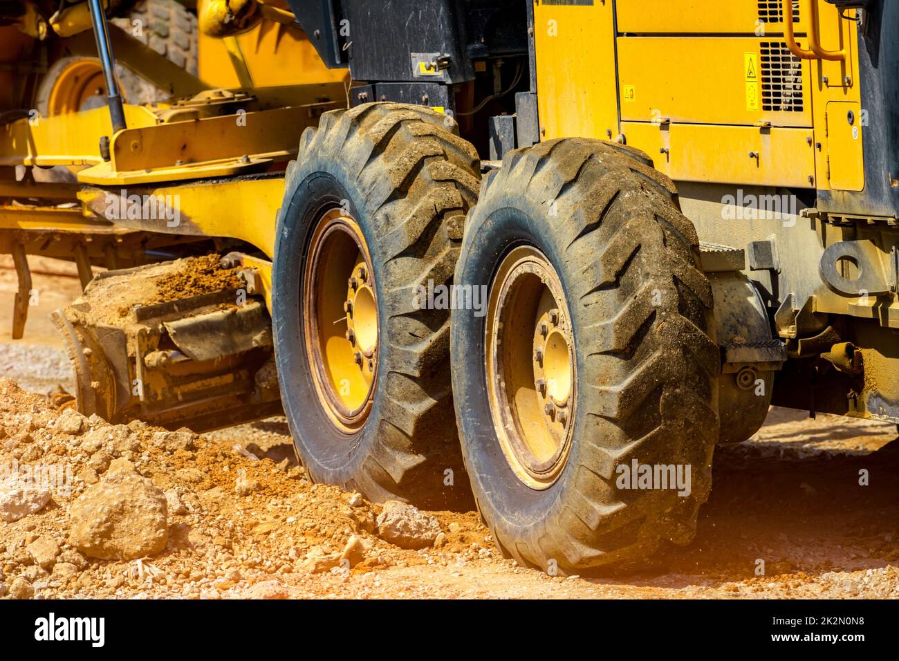 Livellatore stradale che lavora in cantiere per la manutenzione e la costruzione di sporcizia e ghiaia. Motorgrader giallo. Macchinari pesanti e attrezzature per la costruzione per il livellamento di strade. Macchina livellatrice. Foto Stock