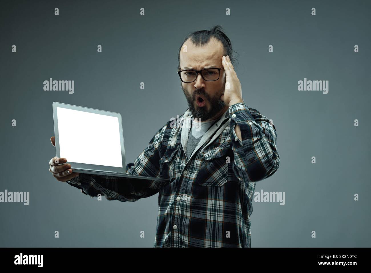 Uomo con un'espressione del viso sbalordita mentre tiene in mano un notebook Foto Stock