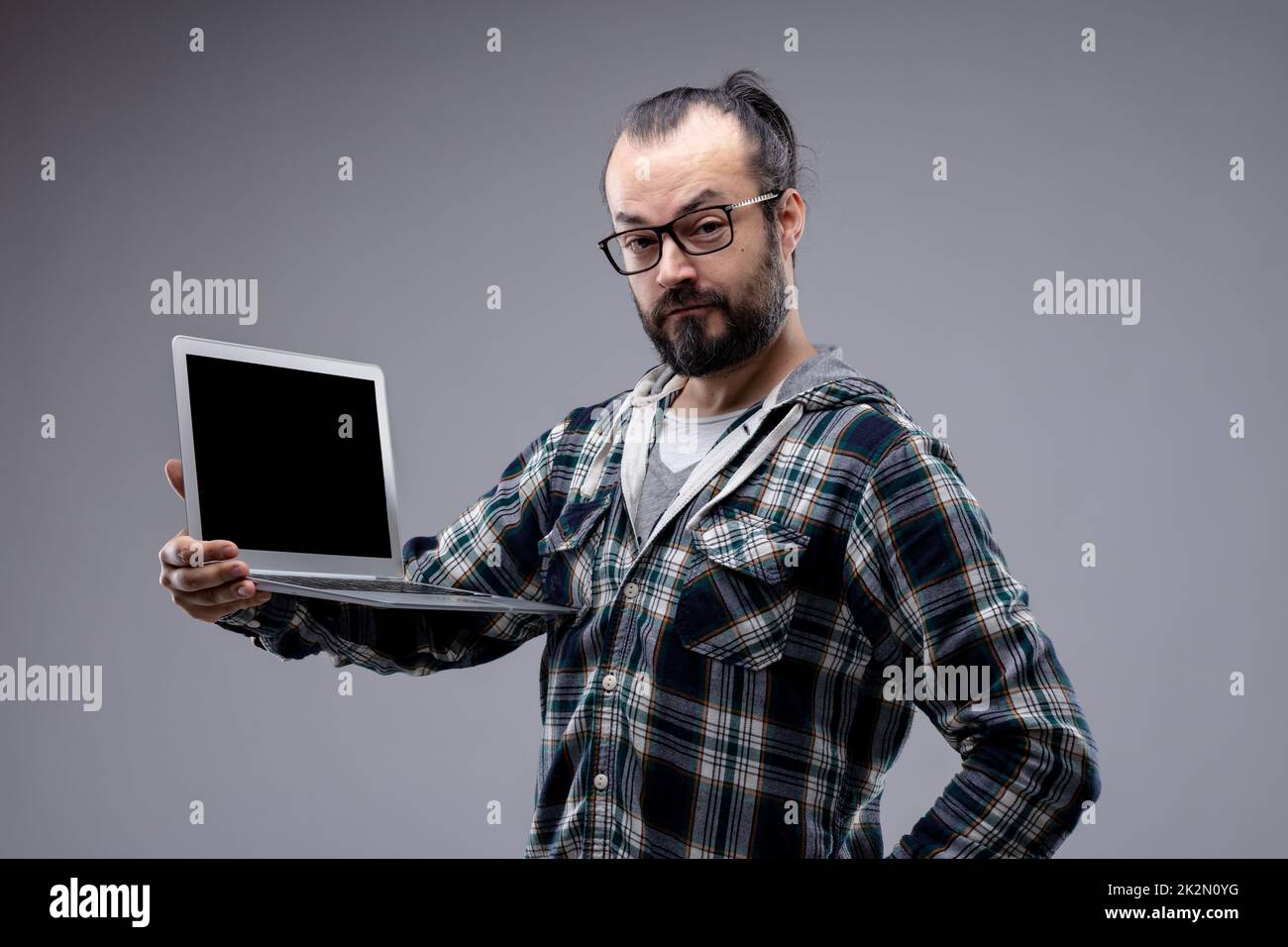 Uomo quizzico che tiene in mostra un computer portatile Foto Stock