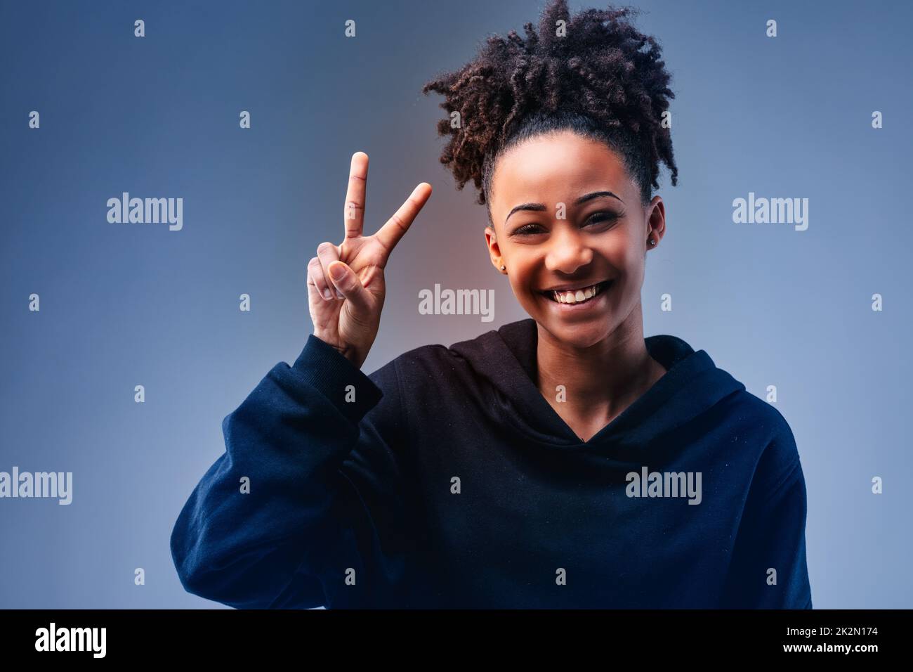 Vivace attraente giovane donna nera che dà un segno V gesto Foto Stock