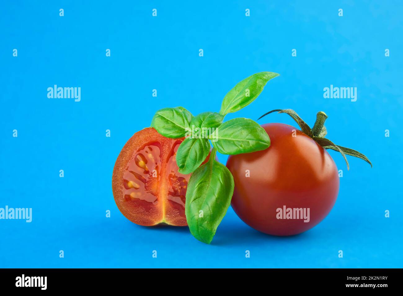 Foglie fresche di basilico verde e pomodori ciliegini Foto Stock