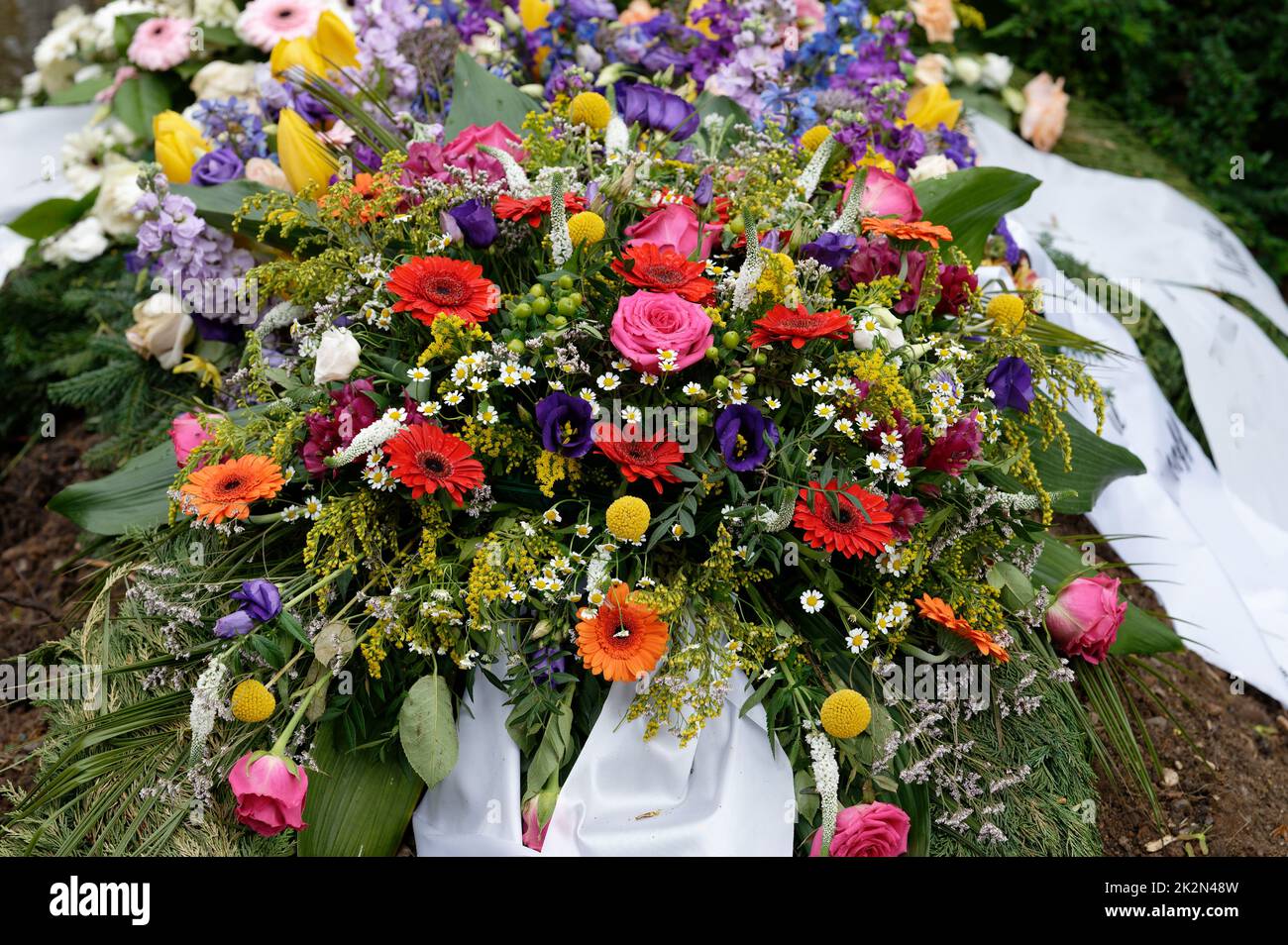 molti fiori colorati su una tomba dopo un funerale Foto Stock