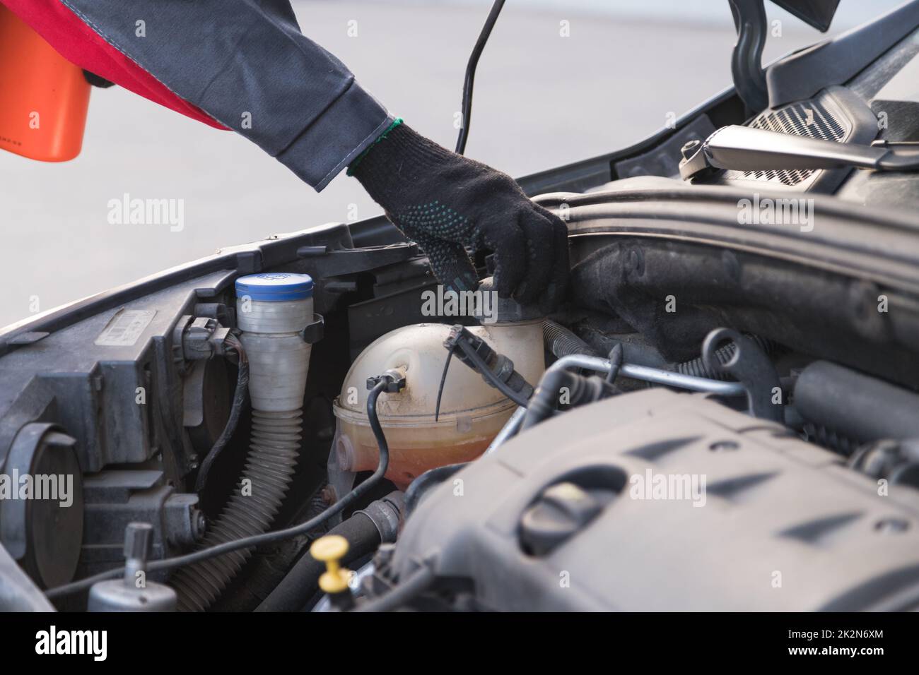 Il meccanico automatico svita il tappo del serbatoio di espansione per versare l'antigelo nell'officina di assistenza auto Foto Stock