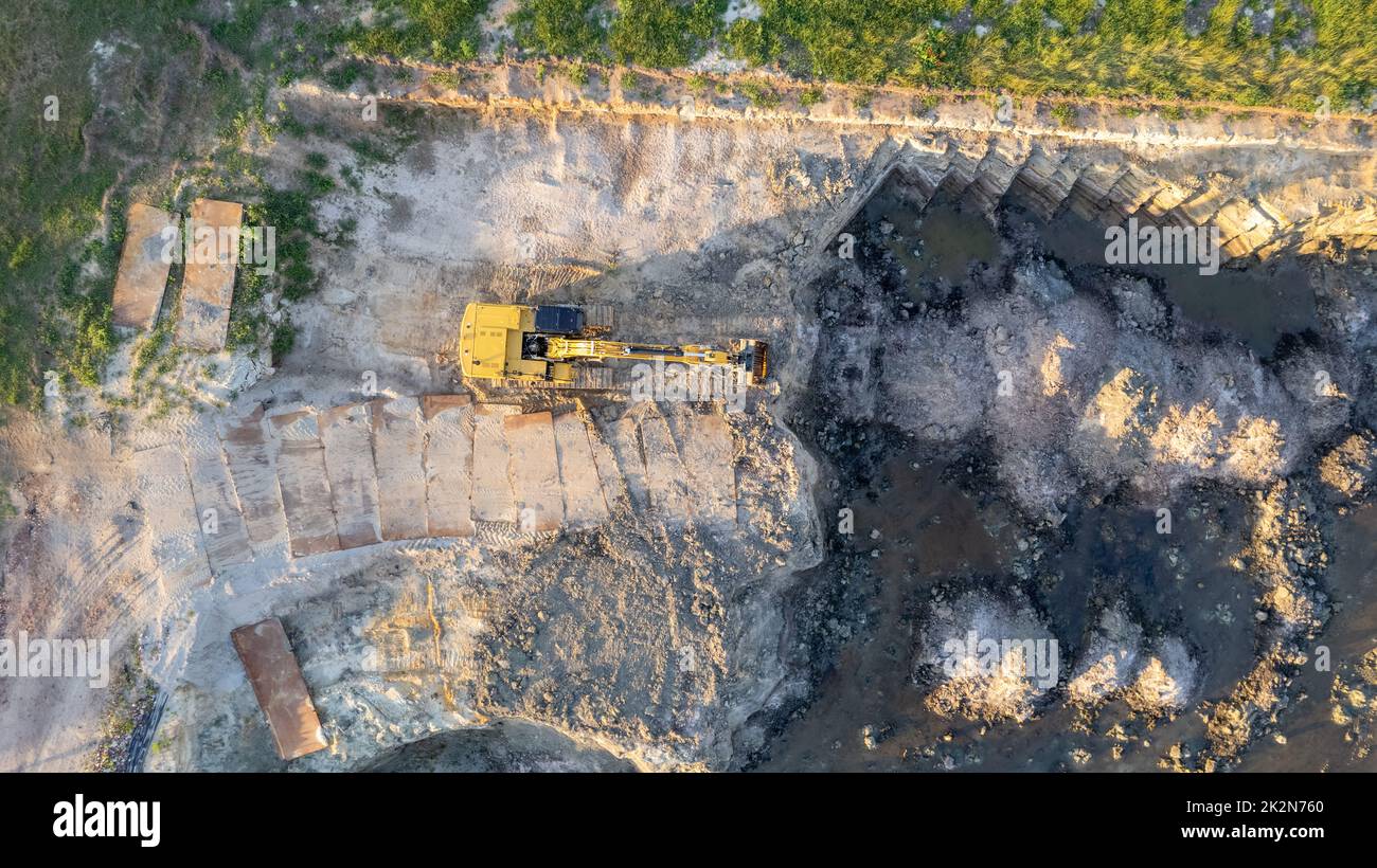 Bulldozer cingolato giallo esegue lavori di terra - ripresa aerea. Il trattore cingolato giallo rastrema il terreno per costruire una strada asfaltata. Il bulldozer di terra lavora durante la costruzione della strada di percorso. Foto di alta qualità Foto Stock