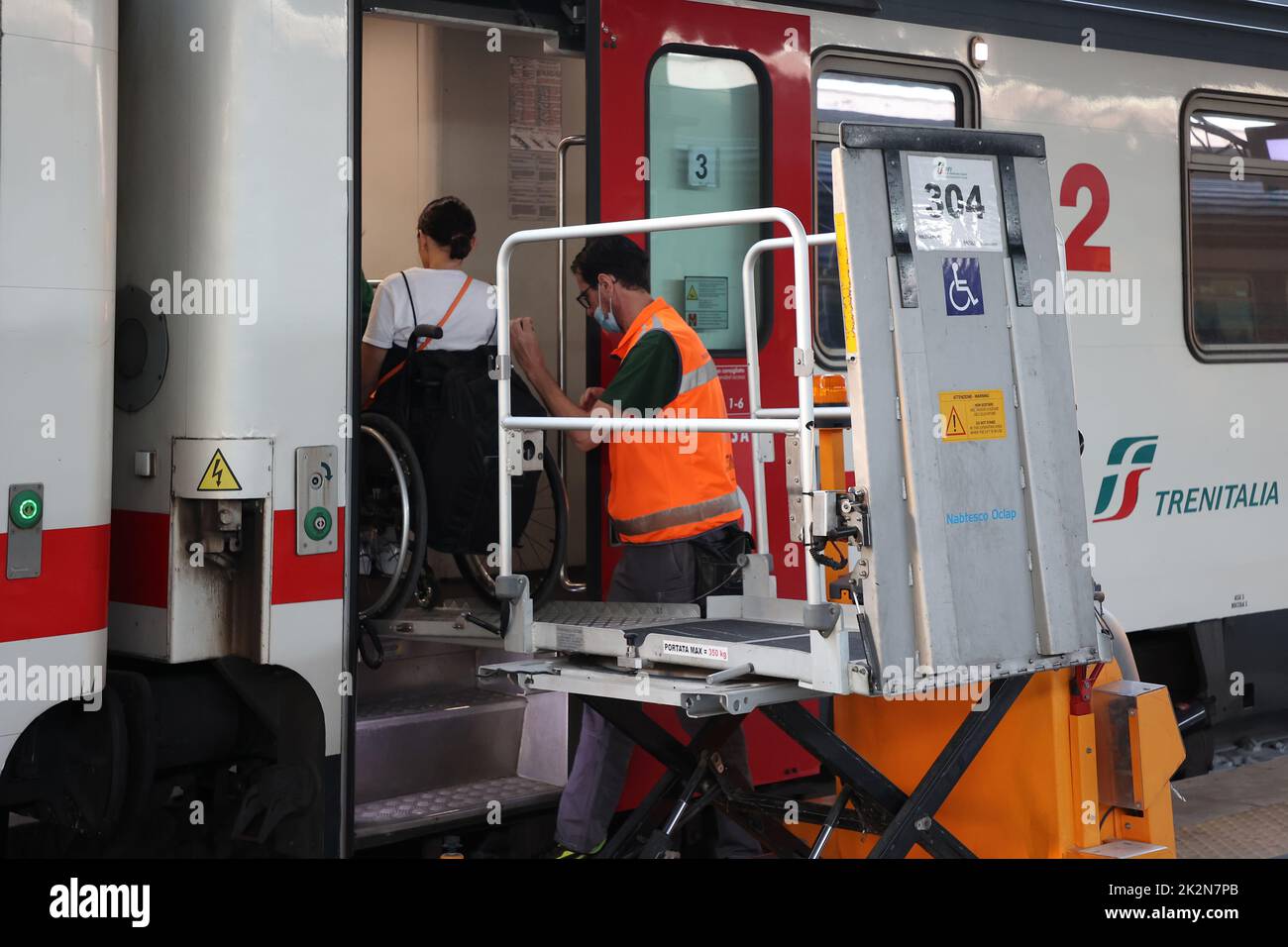 Napoli, Italia - 21 settembre 2022: Nella stazione ferroviaria un passeggero disabile in carrozzina viene trasportato sulla carrozza utilizzando una speciale per Foto Stock