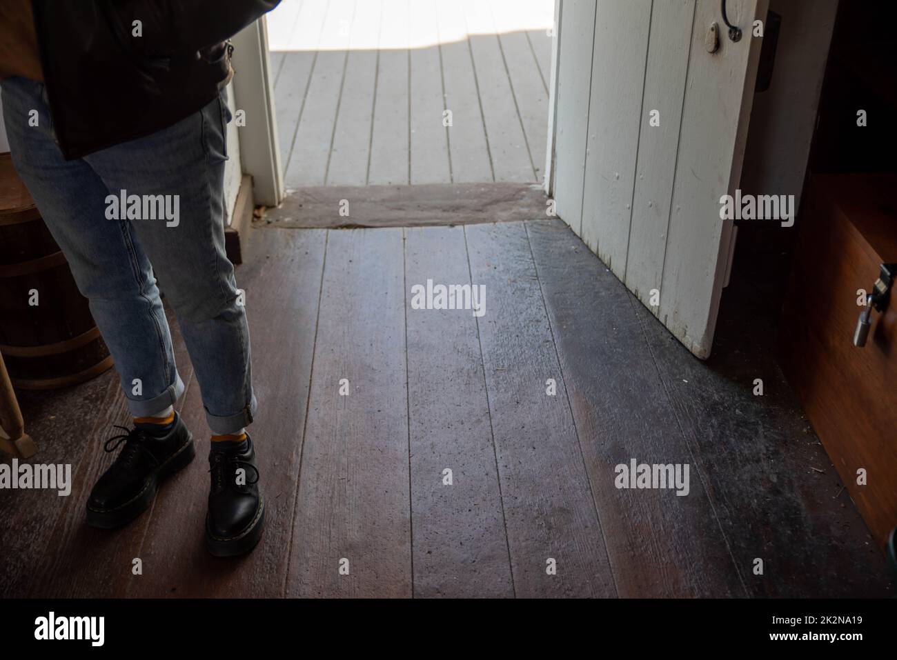 Piedi all'interno dell'ingresso della porta aperta con antichi pavimenti in legno Foto Stock