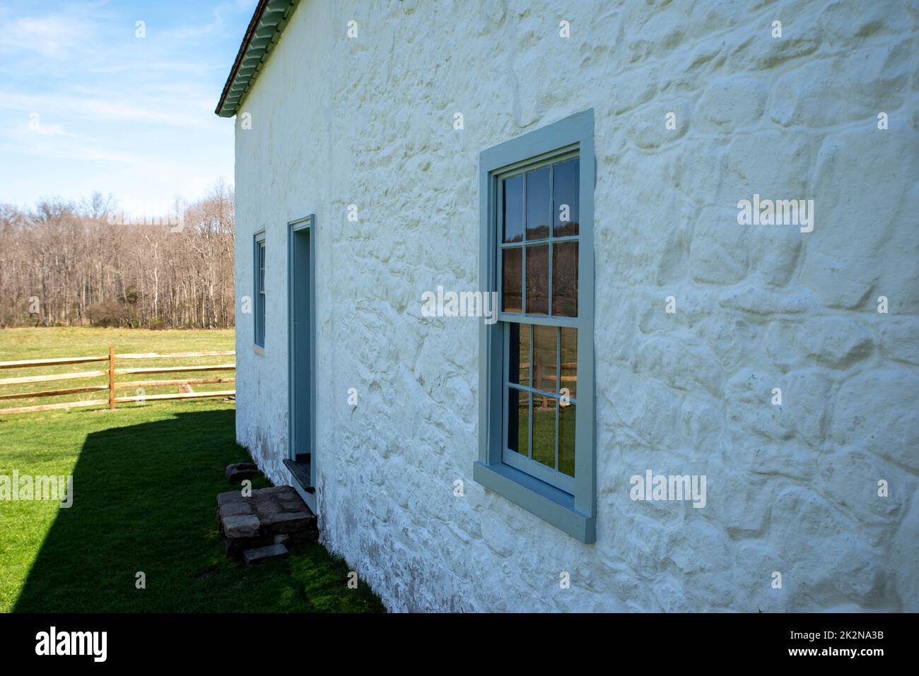 Vista laterale di bianco coloniale americano cottage in pietra nel paesaggio rurale Foto Stock