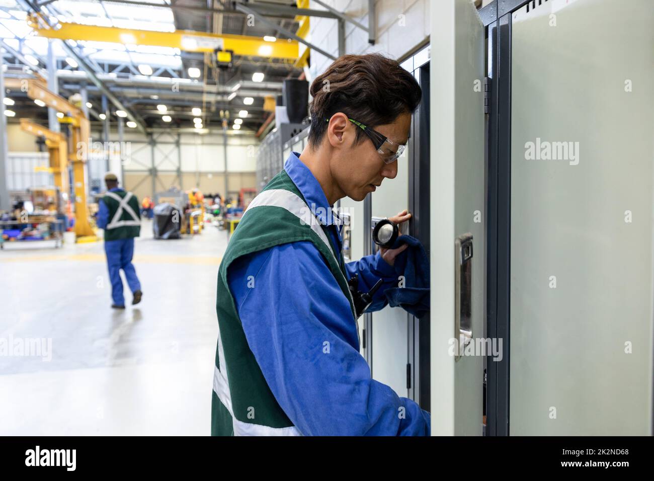 Lavoratore di transito maschile presso un armadietto aperto nell'impianto di manutenzione Foto Stock