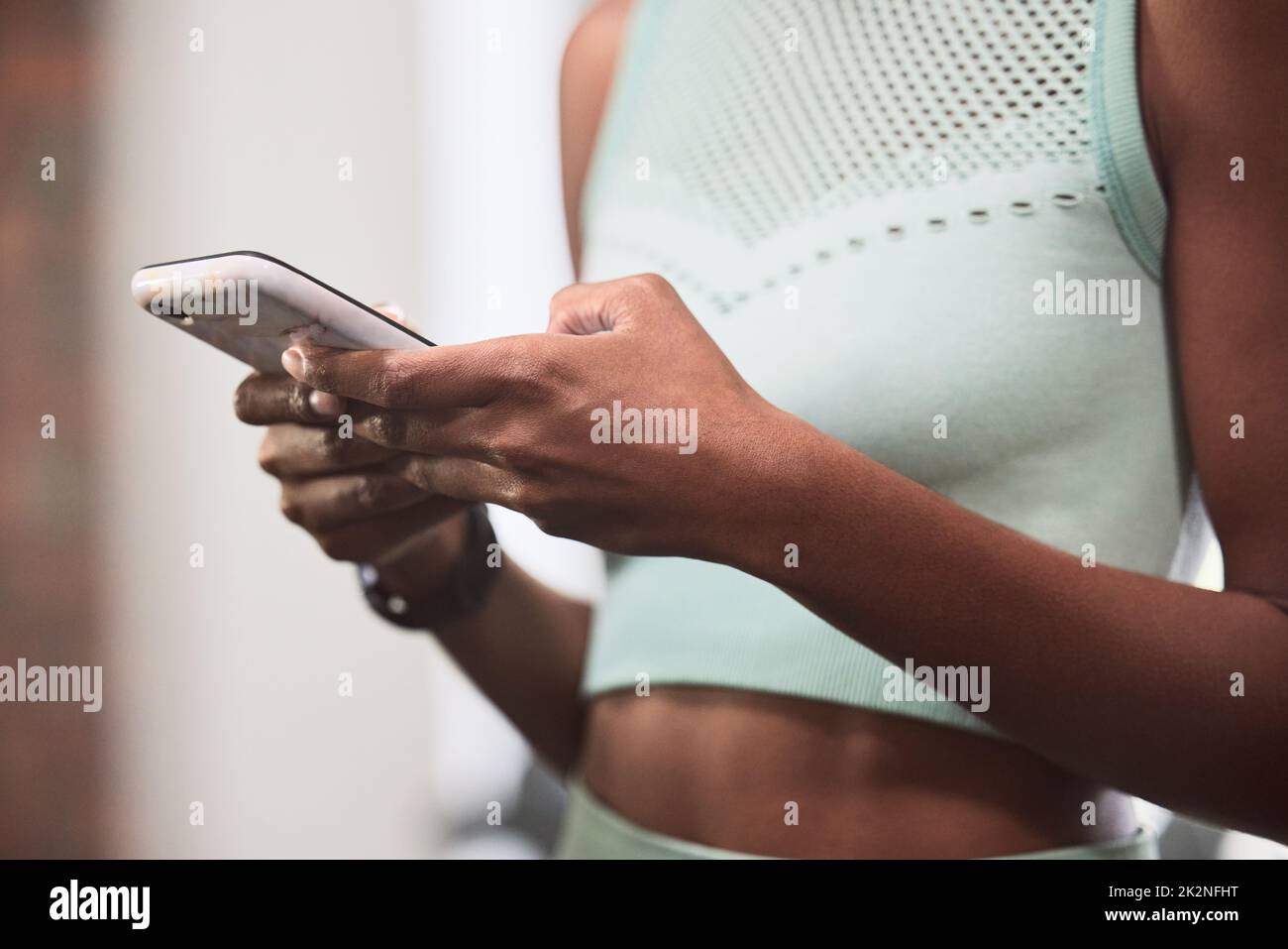 Un personal trainer tascabile. Scatto di una donna irriconoscibile utilizzando uno smartphone durante un allenamento in palestra. Foto Stock