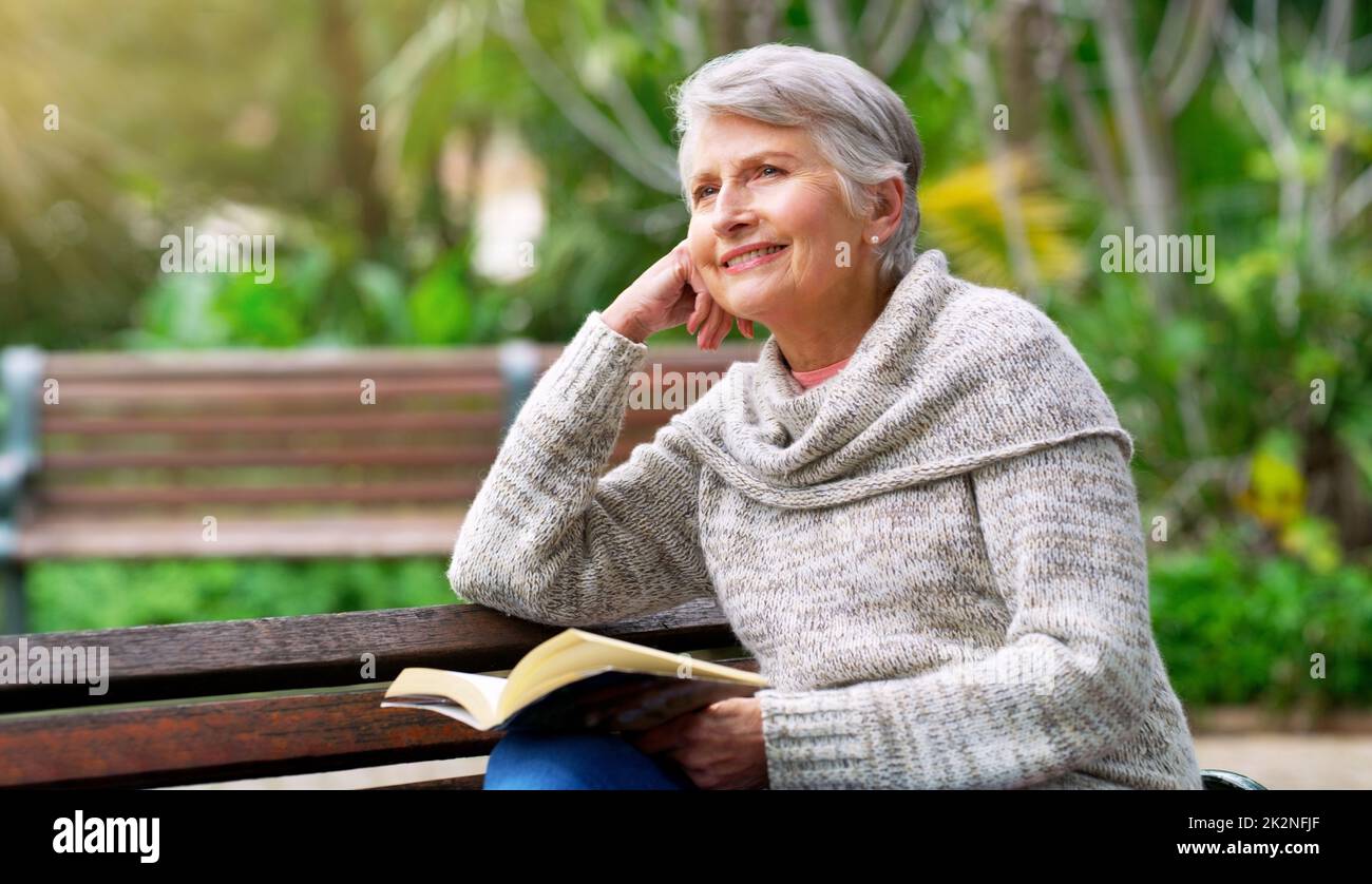 Niente come leggere un libro in pace. Scatto corto di una donna anziana allegra che legge un libro da sé fuori in un parco. Foto Stock