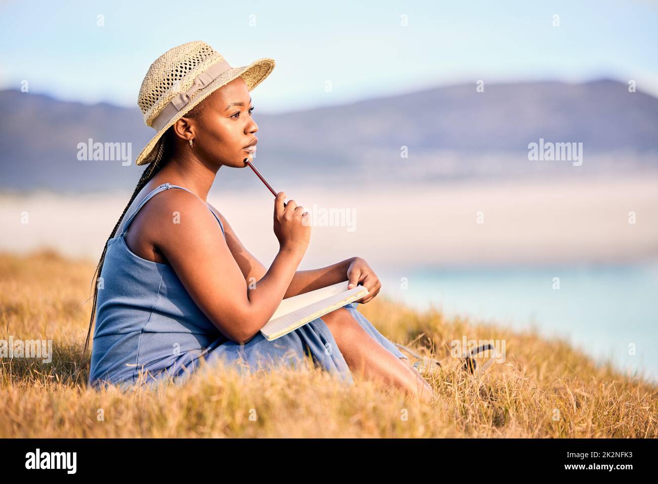 Finestre di dialogo annegate. Scatto di una giovane donna che scrive nel suo diario alla spiaggia. Foto Stock