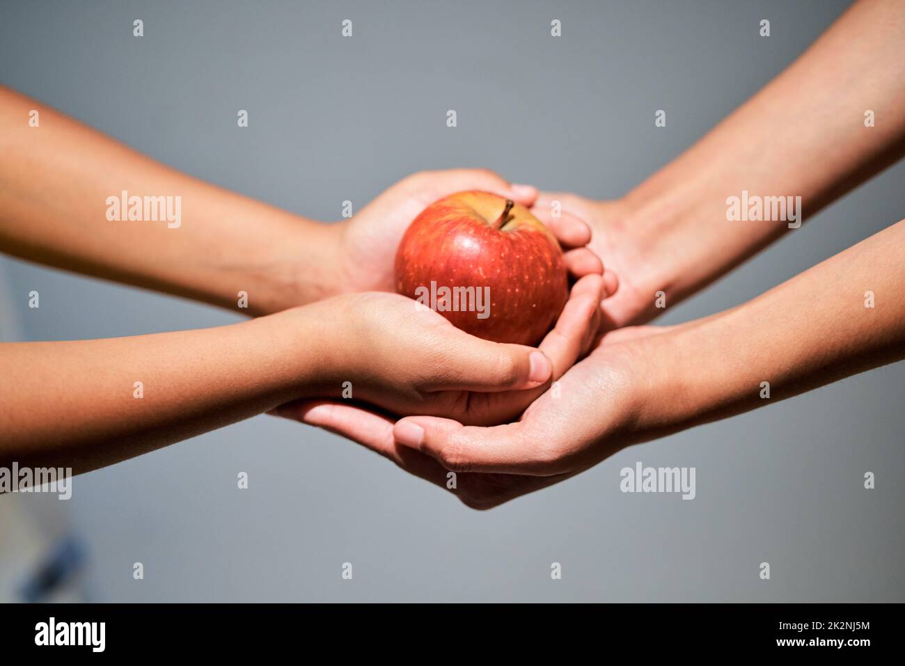 Una mela al giorno.... Studio girato di una donna irriconoscibile dando un bambino una mela. Foto Stock