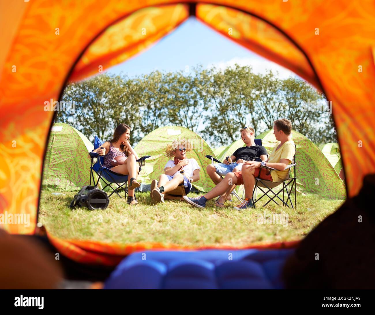 Camping con gli amici è la parte migliore di questo festival. Girato di un gruppo di amici seduti fuori dalla loro tenda in un festival. Foto Stock