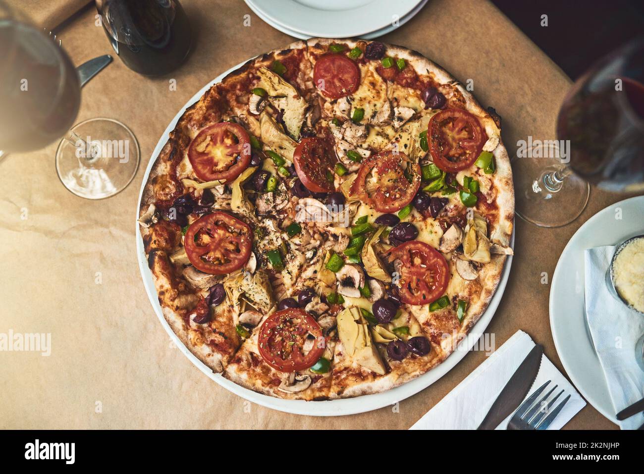 Avere una fetta. Shot ad angolo alto di un piatto completo di pizza appoggiato su un tavolo all'interno di un ristorante durante il giorno. Foto Stock