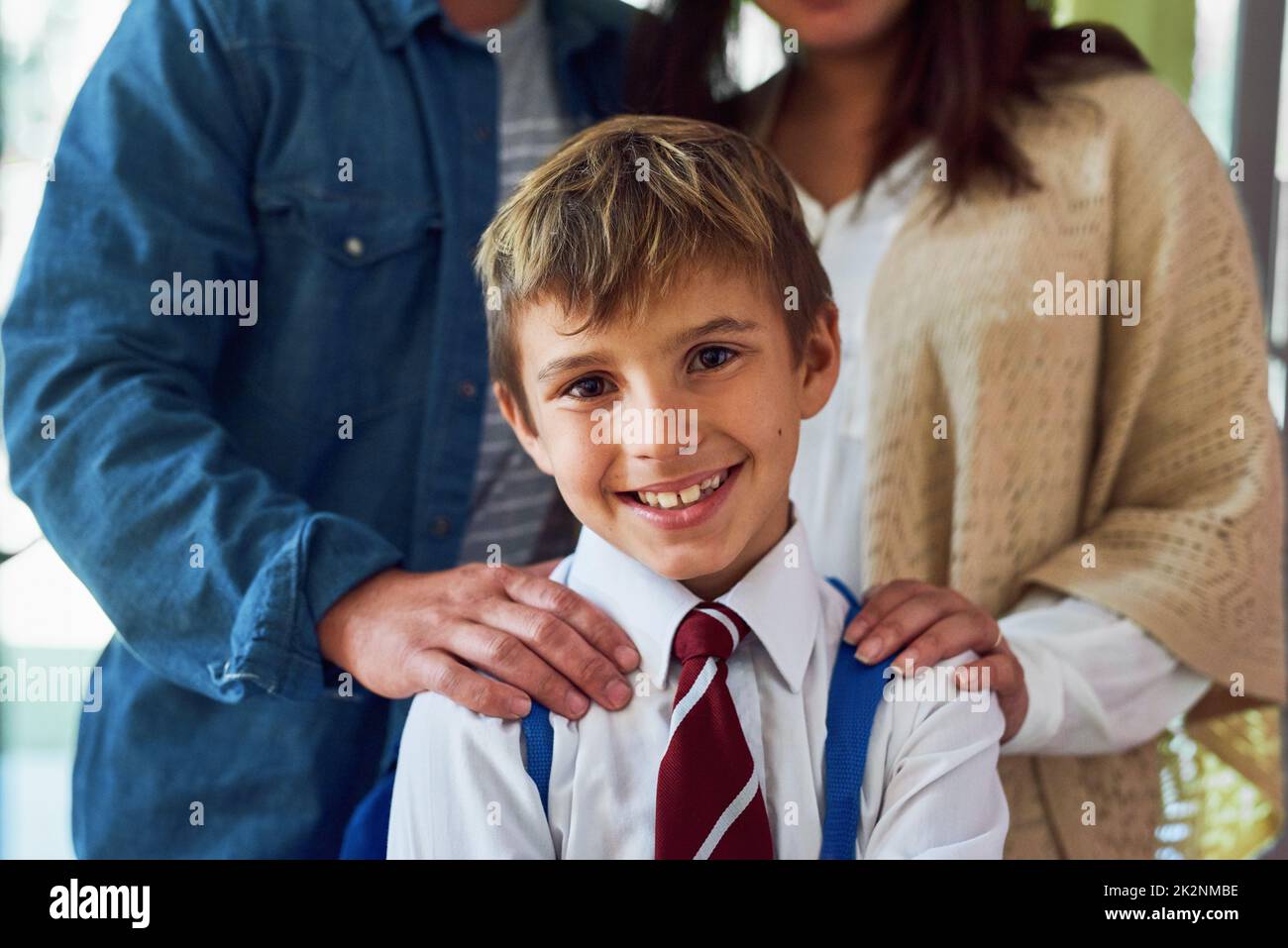 Pronto per la scuola. Colpo di un giovane scolaro in piedi con i genitori. Foto Stock