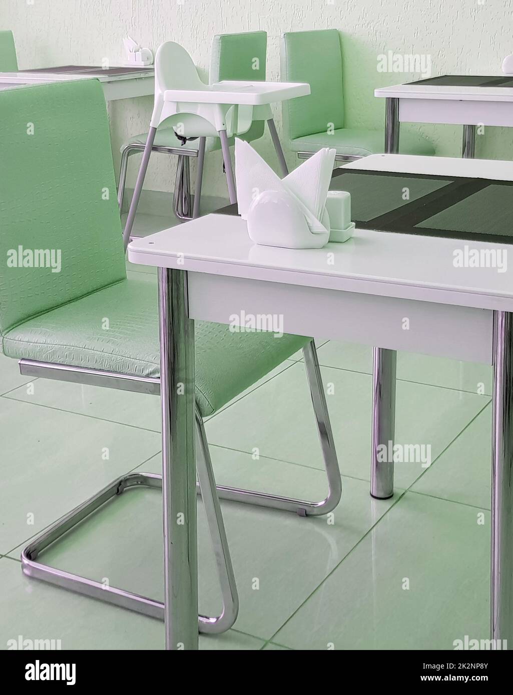 Interni eleganti e moderni della sala da pranzo con tavoli e sedie di design, tintura verde Foto Stock