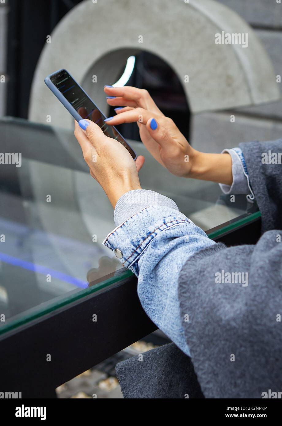 La ragazza si siede in un bar e tiene un telefono touch, un robot e la comunicazione via Internet. Robot online, accesso remoto. Foto Stock