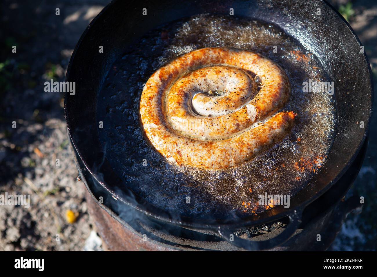 Salsicce di maiale fatte in casa in una padella rustica con spezie diverse. Attività ricreative all'aperto. Foto Stock