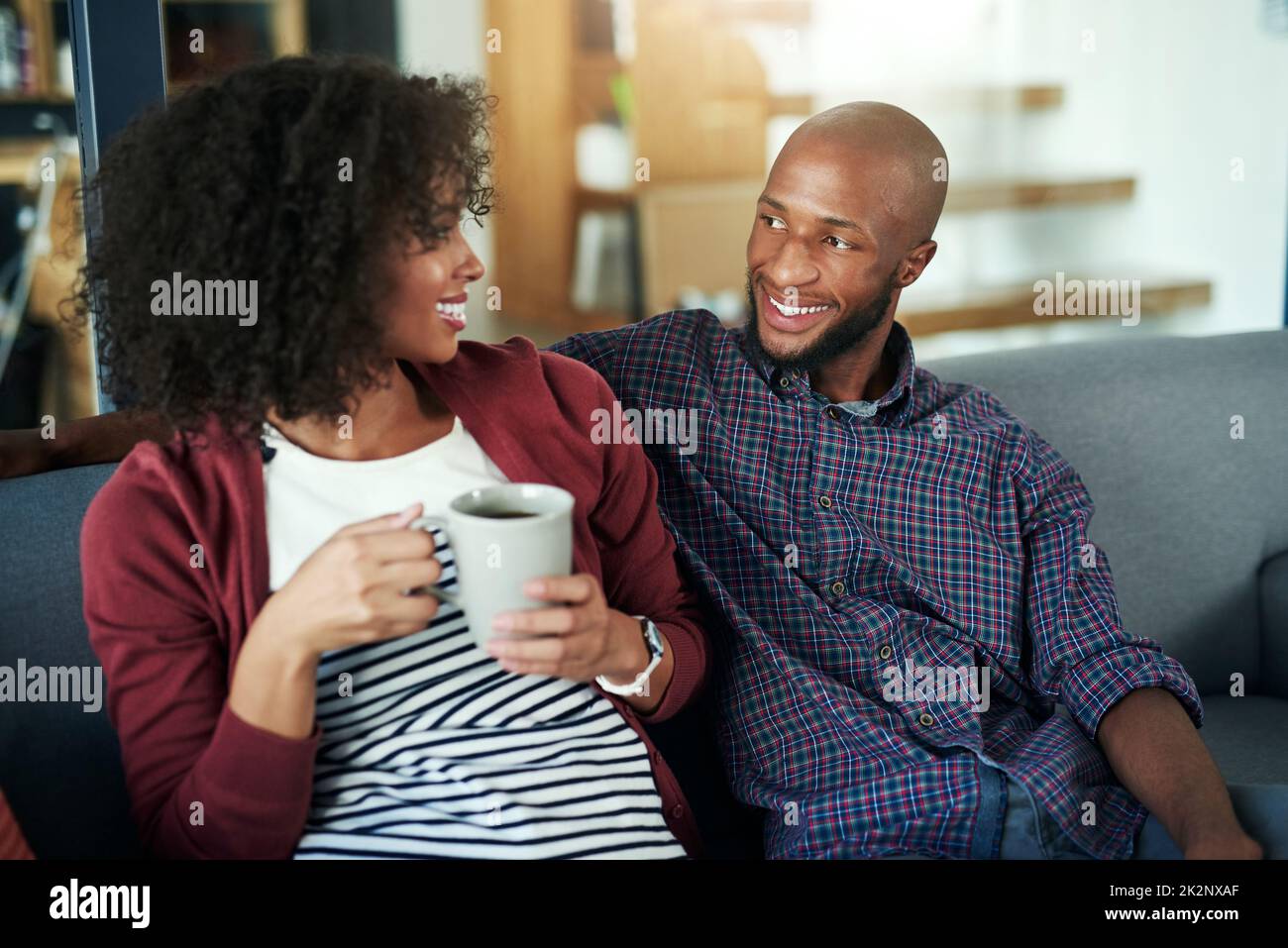 Il fine settimana è il momento ideale per trascorrere un soggiorno di qualità. Scatto di una giovane coppia felice godendo una pausa caffè rilassante insieme sul divano a casa. Foto Stock