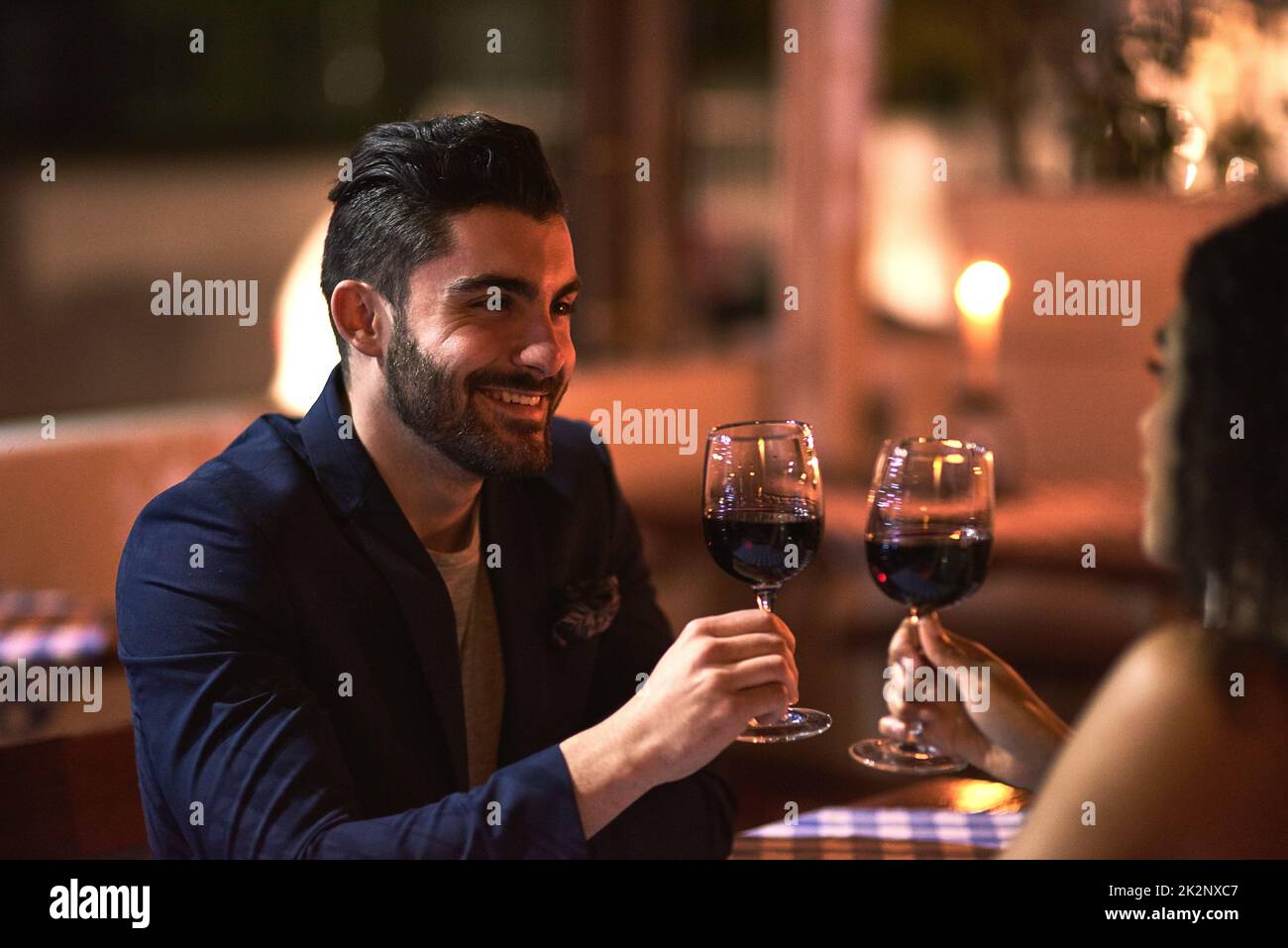 Una bella serata fuori. Scatto di una giovane coppia allegra che ha un brindisi celebrativo con i calici del vino mentre guardandosi negli occhi altri sopra la cena fuori alla notte. Foto Stock