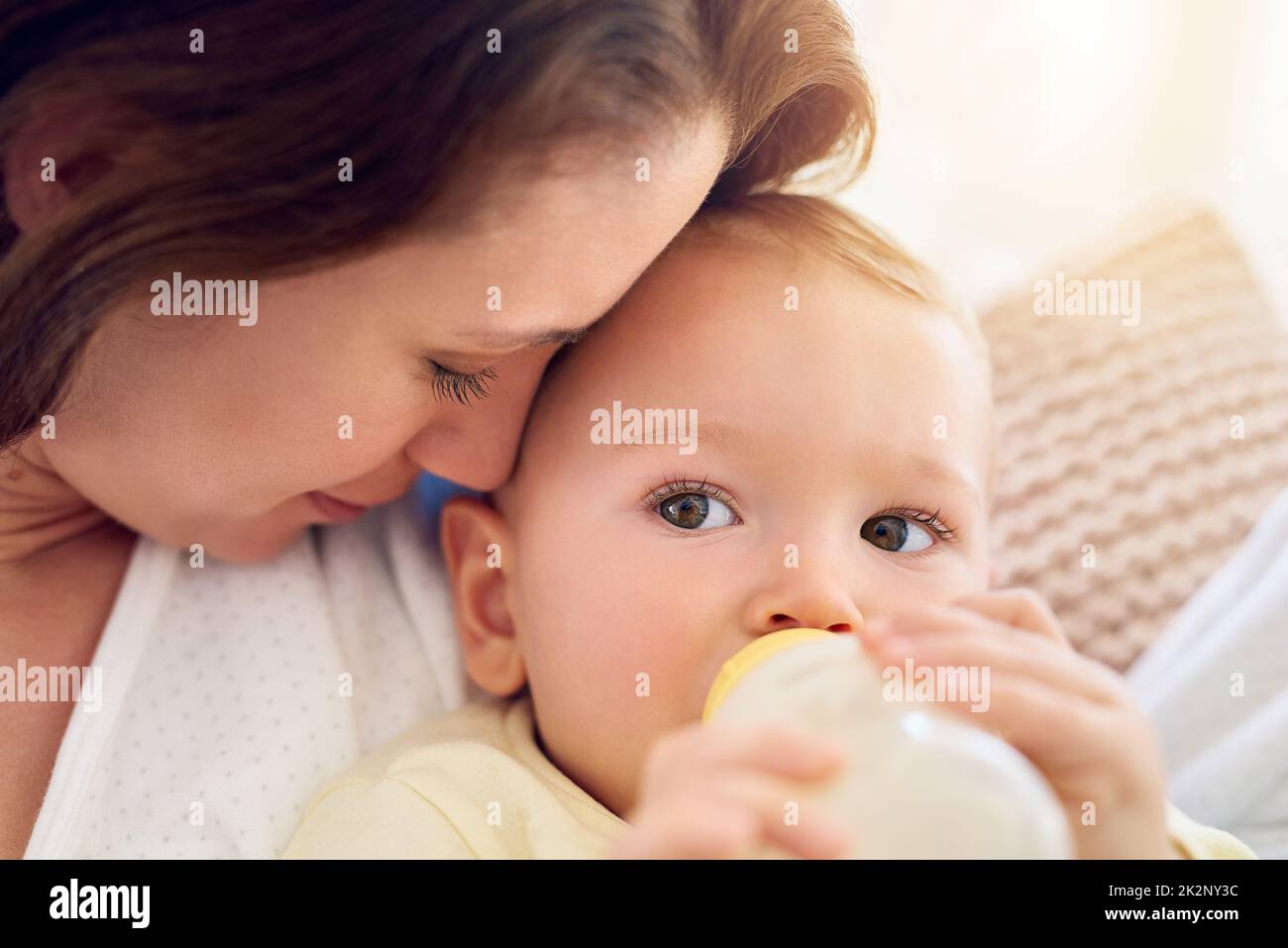 A voi piaceva il piccolo. Shot di un bambino che beve il suo biberon mentre si trova nelle braccia delle madri. Foto Stock