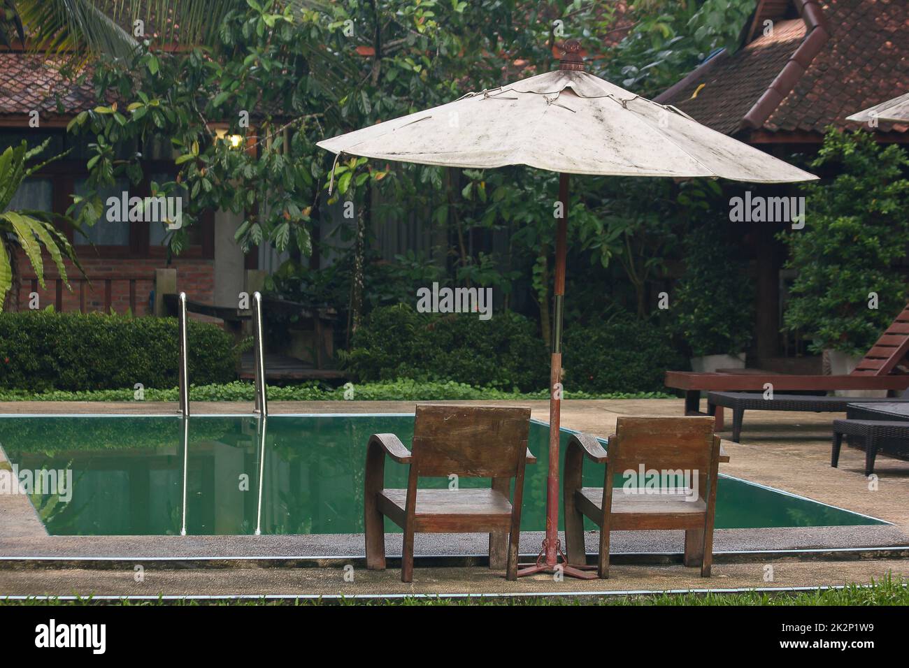 Due sedie in legno si trovano accanto alla piscina. Foto Stock