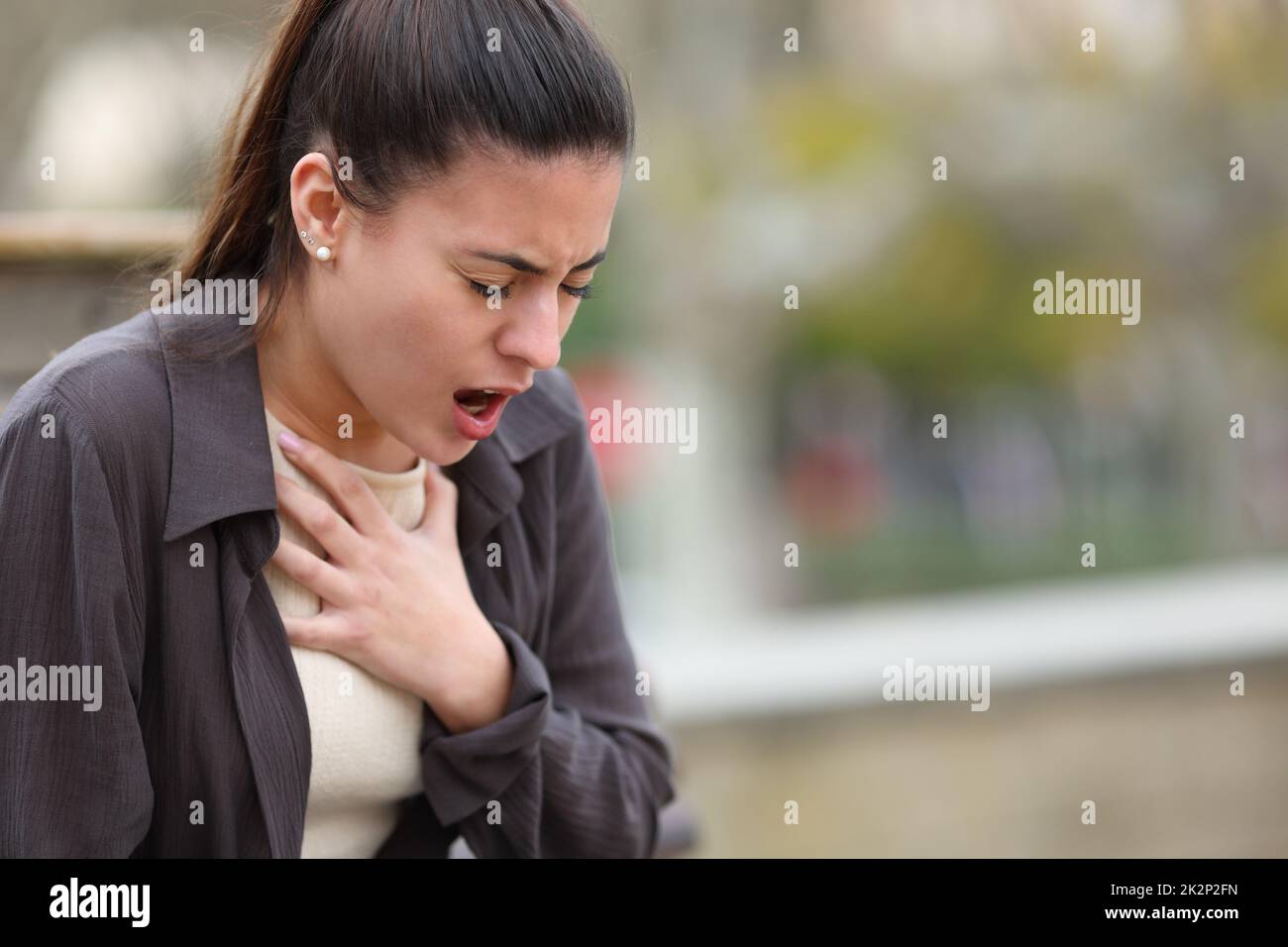 Donna stressata che ha problemi a respirare in un parco Foto Stock