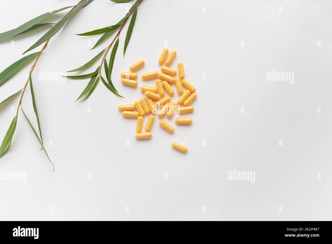 Le compresse gialle di integratori alimentari si trovano su uno sfondo bianco. Luogo per un'iscrizione. Linea verde sullo sfondo. Foto Stock