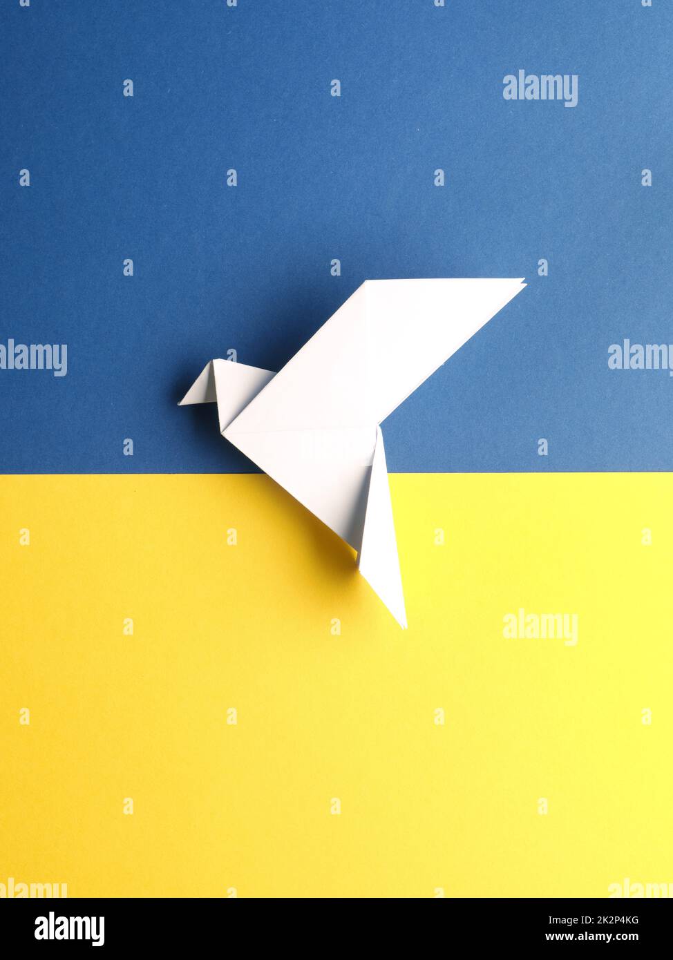 Simbolo di pace con una colomba di origami su carta blu e gialla Foto Stock