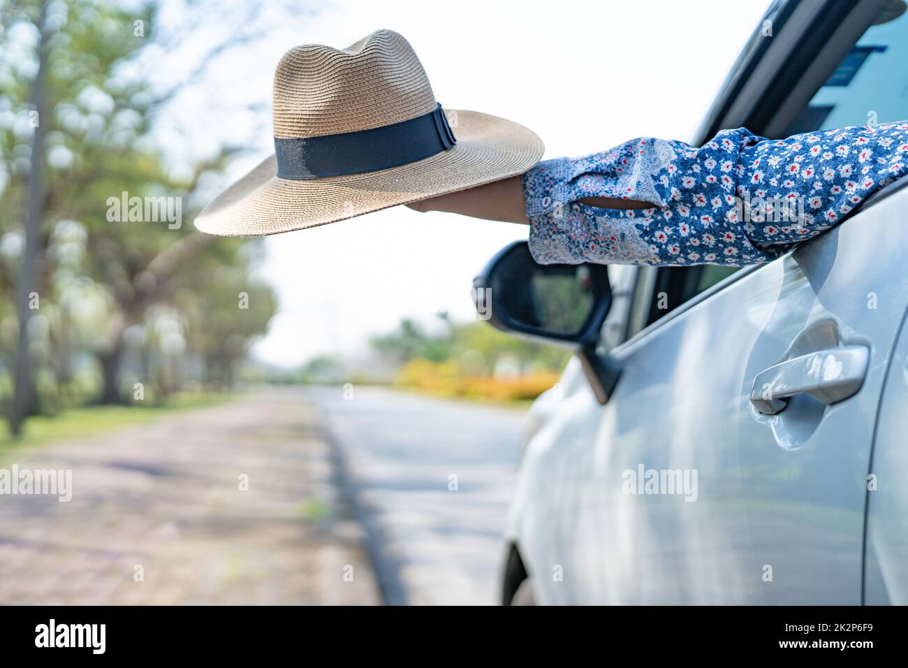 Buon divertimento e libertà nel viaggio con mano rialzata e tenendo un bel cappello fuori dalla vetrina in vacanza estiva Foto Stock