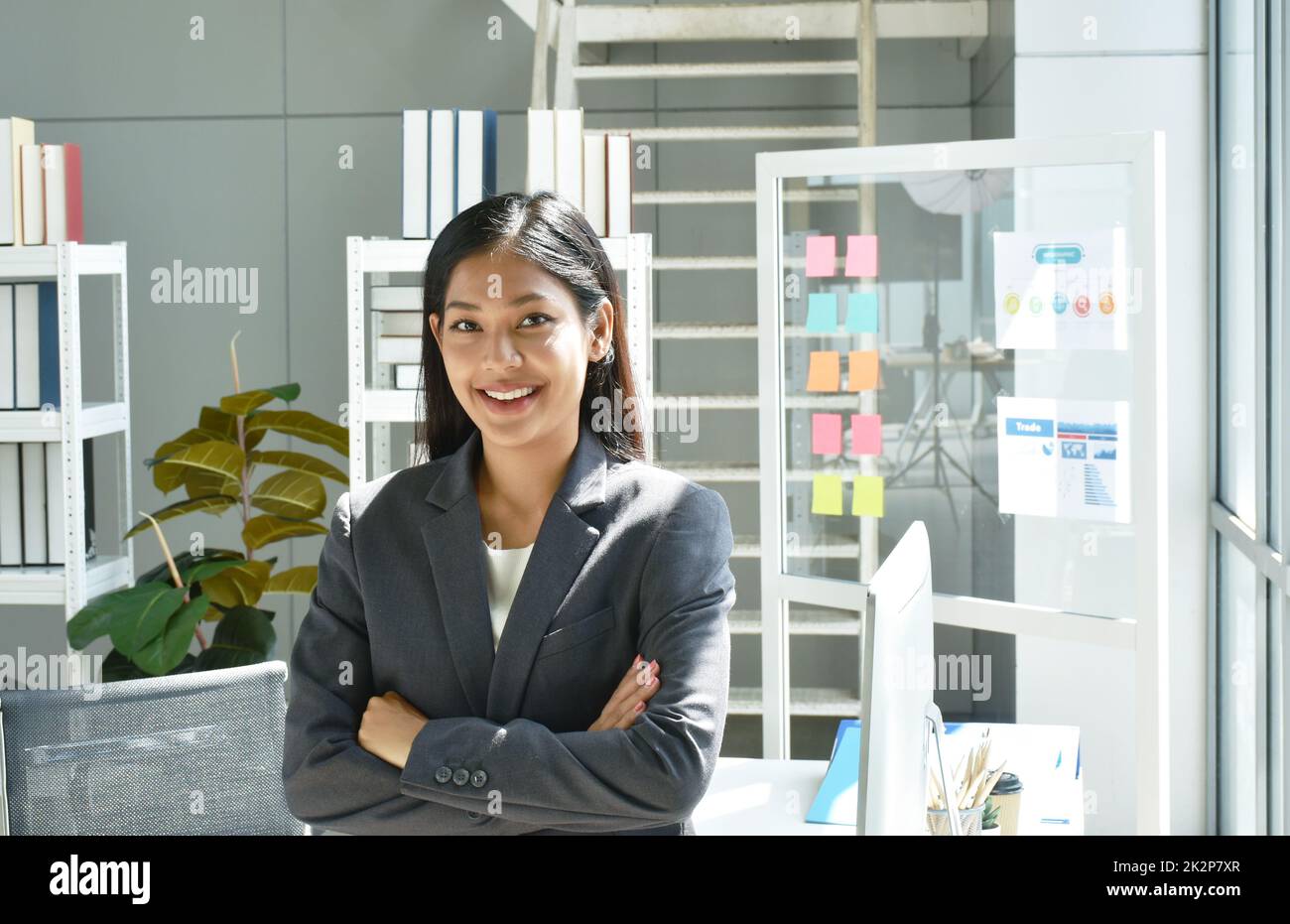 Felice bella donna asiatica busimess posa in vetro sfondo finestra con successo momento in ufficio Foto Stock