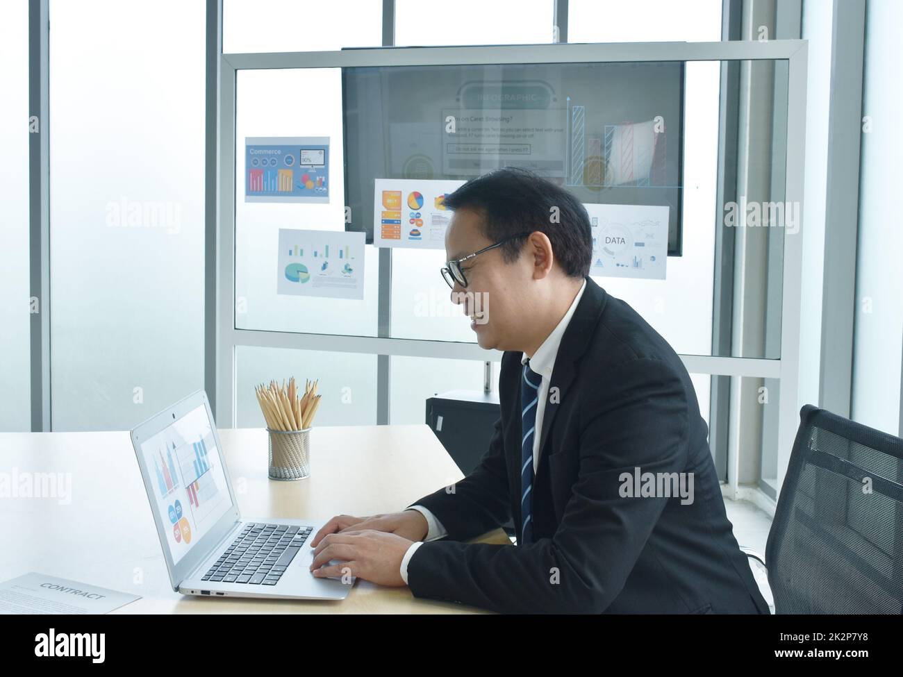 Buon uomo d'affari asiatico che usa un computer portatile in ufficio Foto Stock