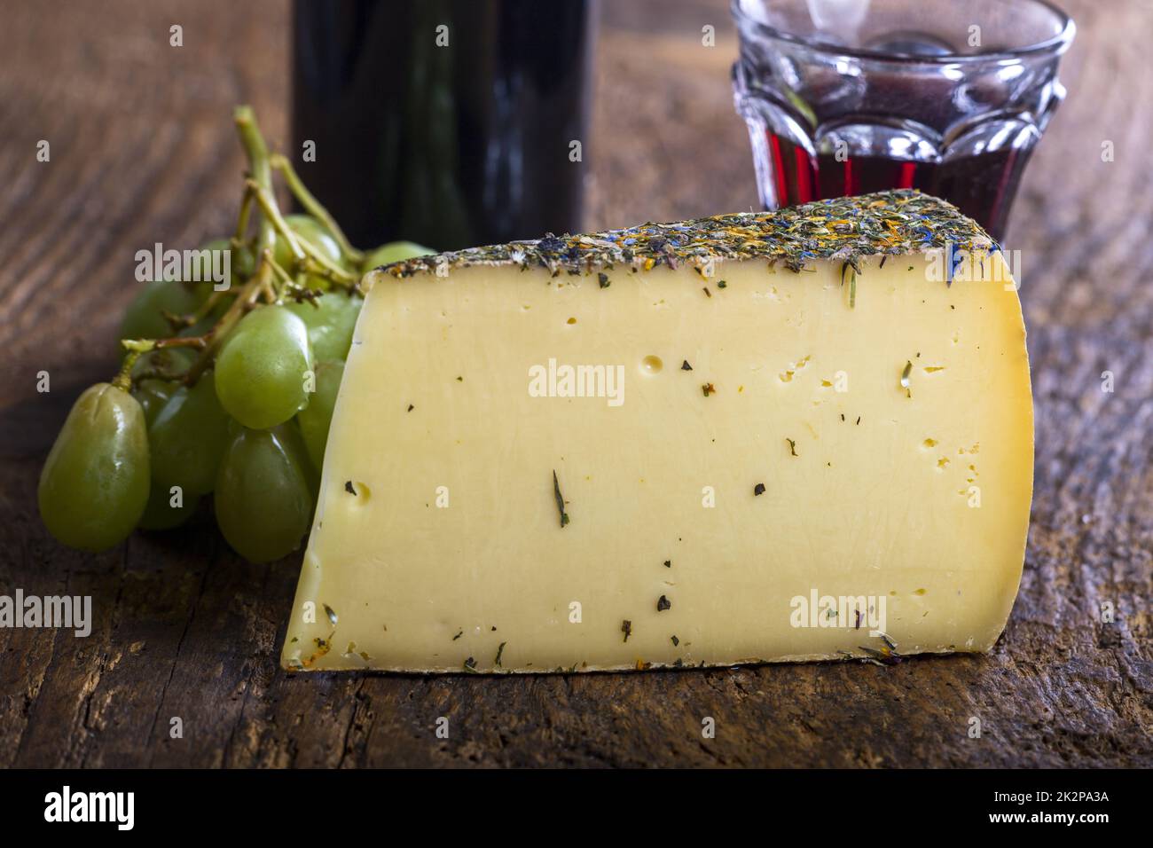 formaggio di montagna con uva su legno Foto Stock