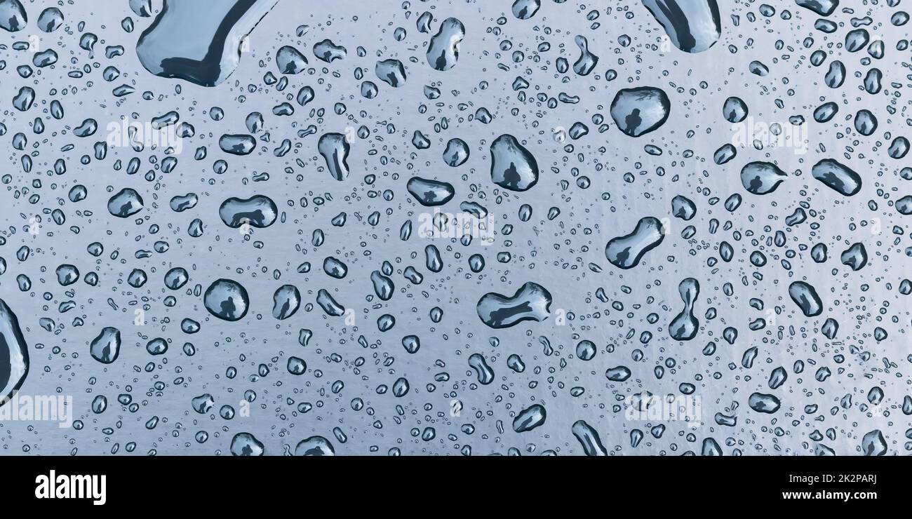 Silhouette di un uomo in gocce d'acqua. Finestra bagnata, gocce di pioggia su vetro blu. Sfondo piovoso. Autunno sfondo astratto. Pioggia, primo piano, clima freddo. F Foto Stock