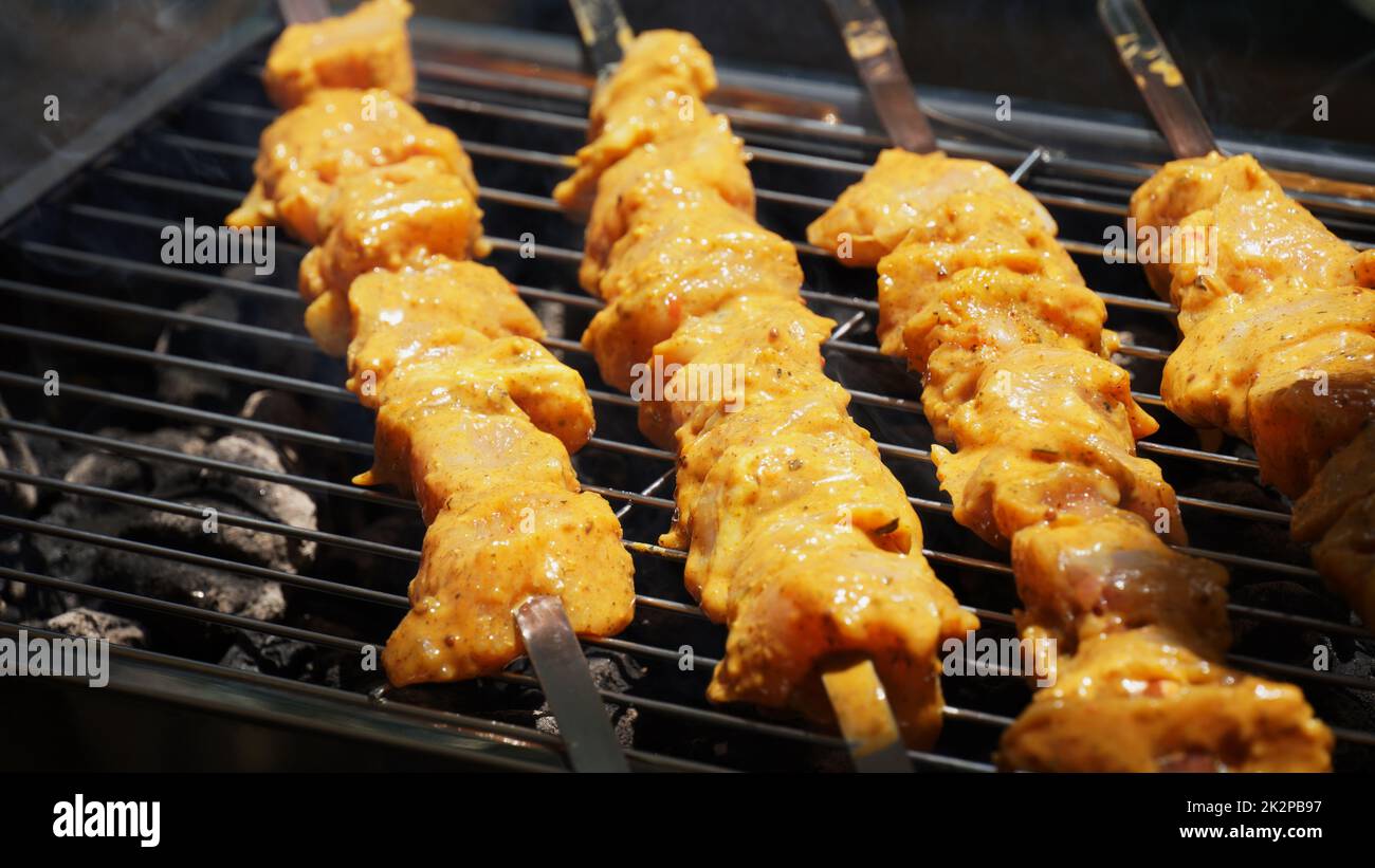 Shashlik - tradizionale barbecue Georgiano. Primo piano di carne cruda arrostita marinata barbecue shish kebab shashlik su spiedini di metallo d'acciaio giacendo griglia fuoco brazier con carbone. Fare barbecue Foto Stock