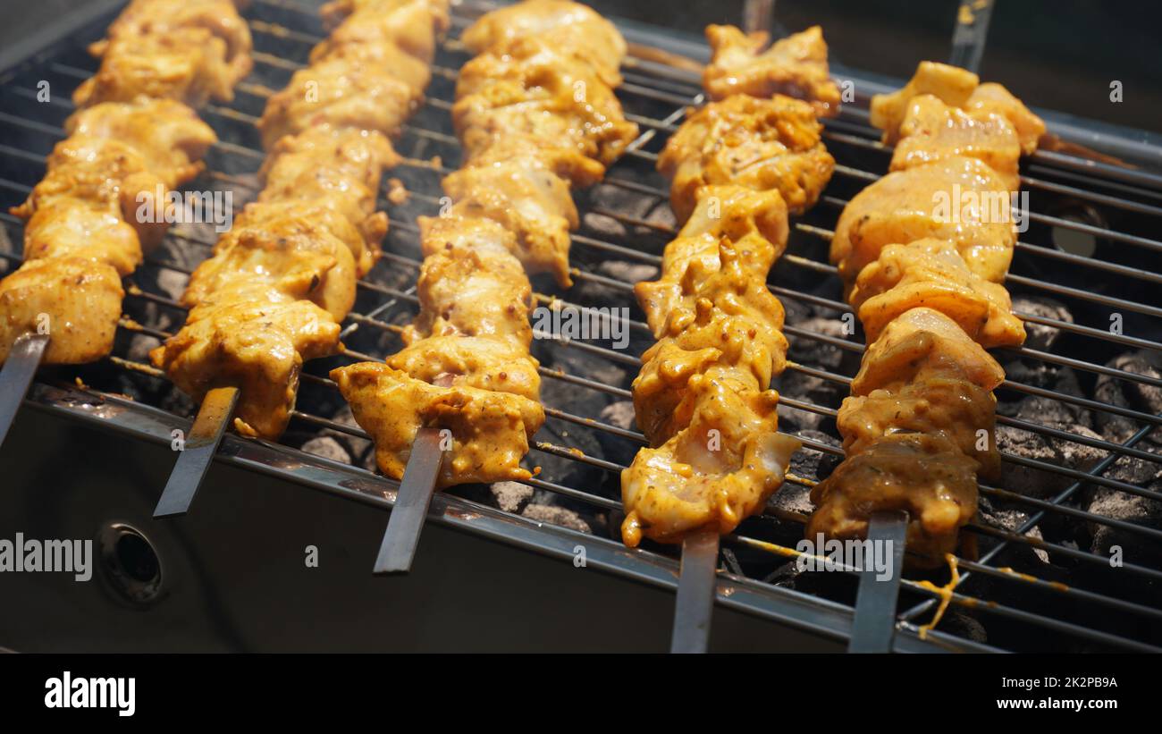 Shashlik - tradizionale barbecue Georgiano. Primo piano di carne cruda arrostita marinata barbecue shish kebab shashlik su spiedini di metallo d'acciaio giacendo griglia fuoco brazier con carbone. Fare barbecue Foto Stock