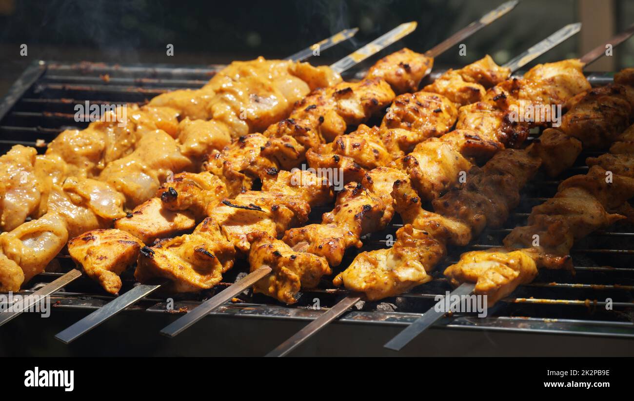 Shashlik - tradizionale barbecue Georgiano. Primo piano di carne cruda arrostita marinata barbecue shish kebab shashlik su spiedini di metallo d'acciaio giacendo griglia fuoco brazier con carbone. Fare barbecue Foto Stock