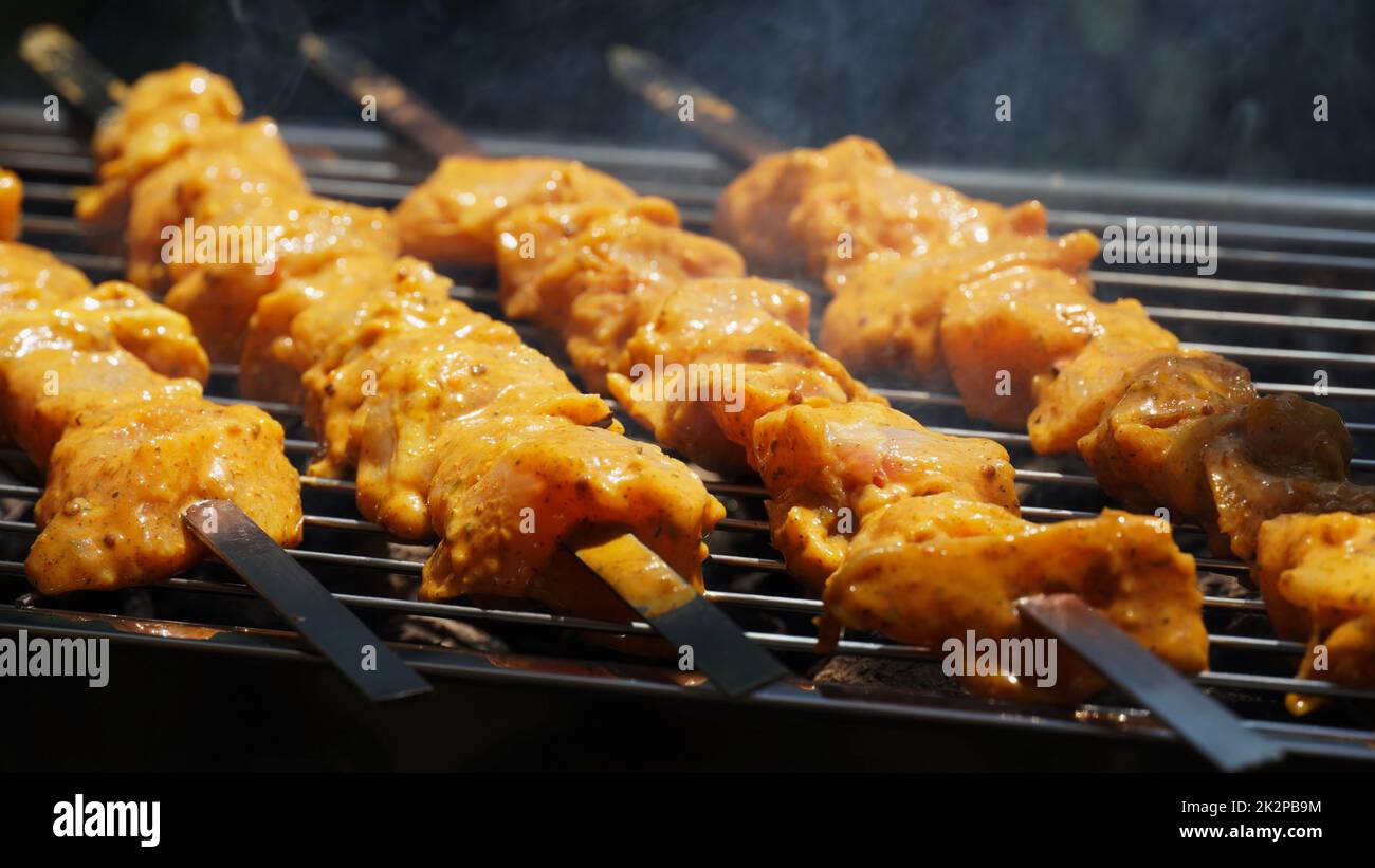 Shashlik - tradizionale barbecue Georgiano. Primo piano di carne cruda arrostita marinata barbecue shish kebab shashlik su spiedini di metallo d'acciaio giacendo griglia fuoco brazier con carbone. Fare barbecue Foto Stock
