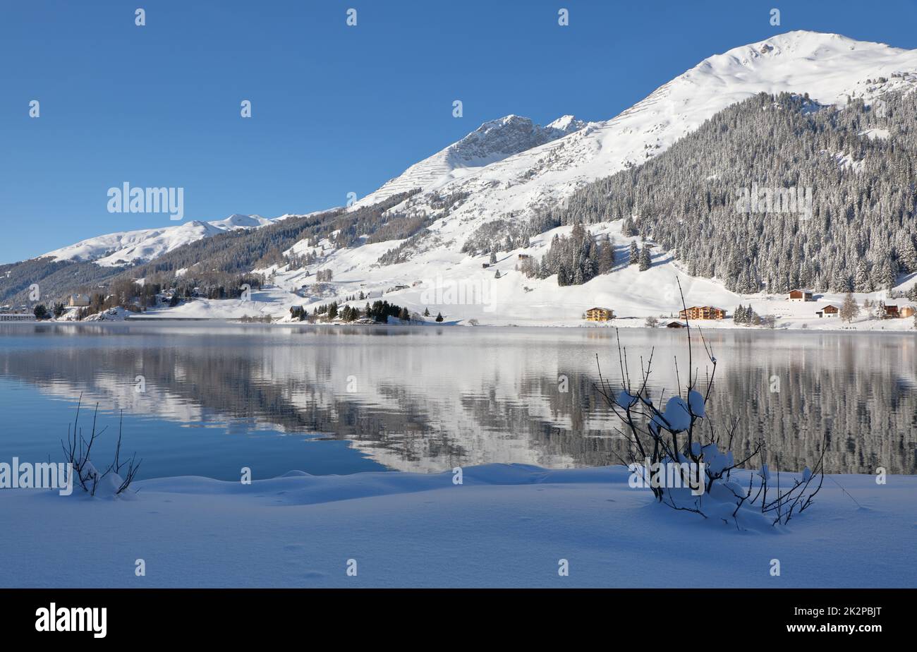 Vista panoramica del paesaggio invernale nelle Alpi con cime innevate che si riflettono nel lago di montagna Foto Stock