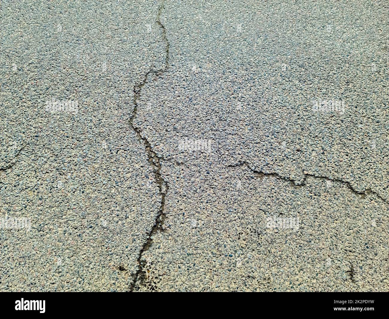 Superfici asfaltate di strade danneggiate e strade con crepe in primo piano. Foto Stock